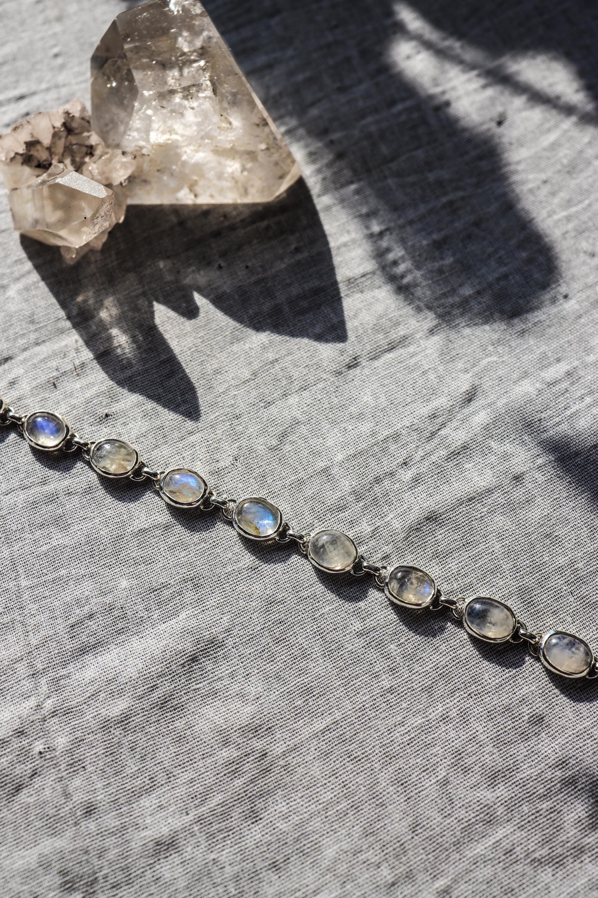 Blue Moonstone bracelet shown as a flowing line of oval cabochons in handmade sterling silver links.