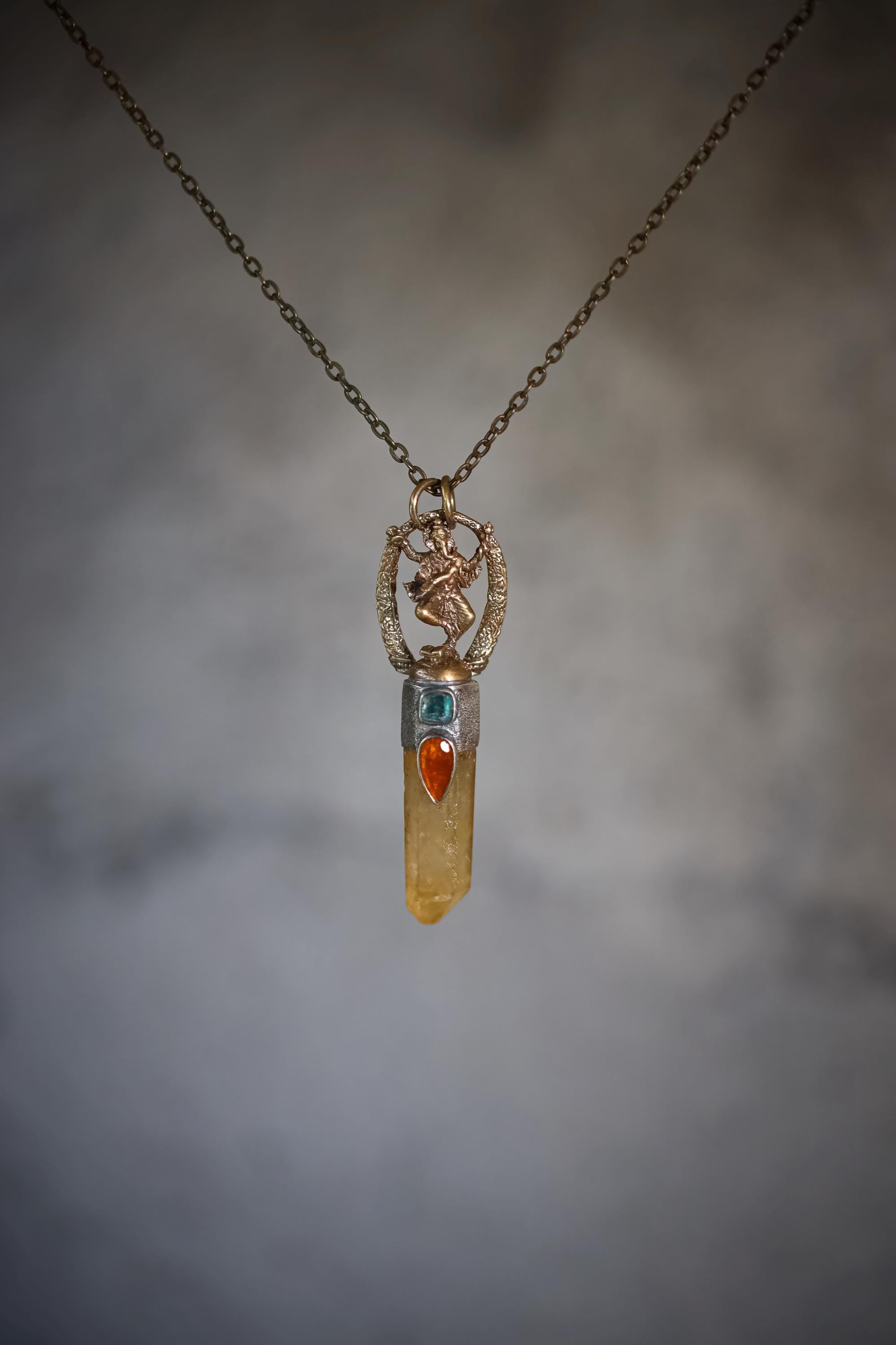 Pendant suspended against gradient grey background capturing crystal clarity and reflection through quartz termination.
