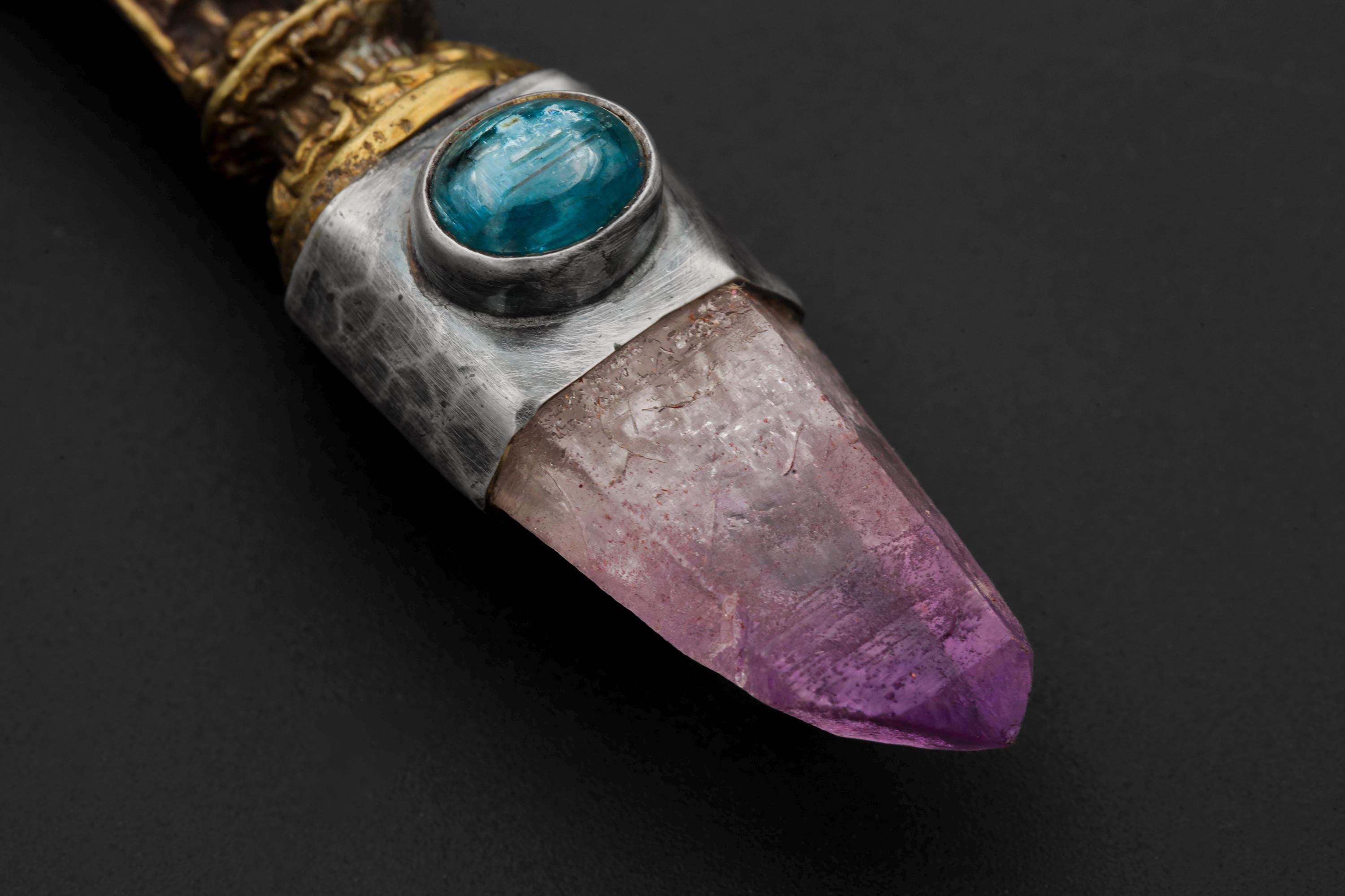Close-up of Vera Cruz Amethyst Laser Point beneath Ocean Kyanite in a Buddha mixed-metal talisman pendant.