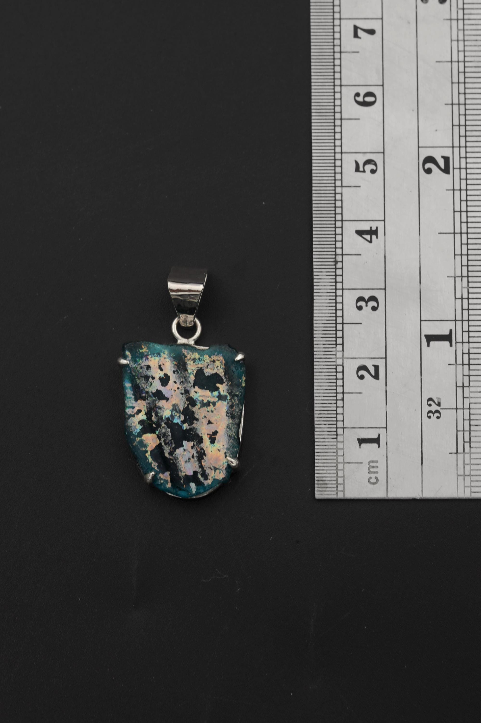 Opalized glass sterling silver pendant shown beside ruler for approximate 4.5 cm size reference.