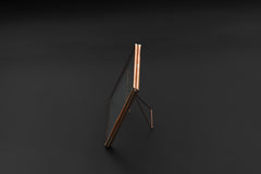 Copper glass photo frame shown on dark background with square shape, slim copper edging, and back stand.
