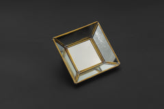 Brass geometric mirror tray shown on dark background with pyramid-style reflective glass panels and square shape.
