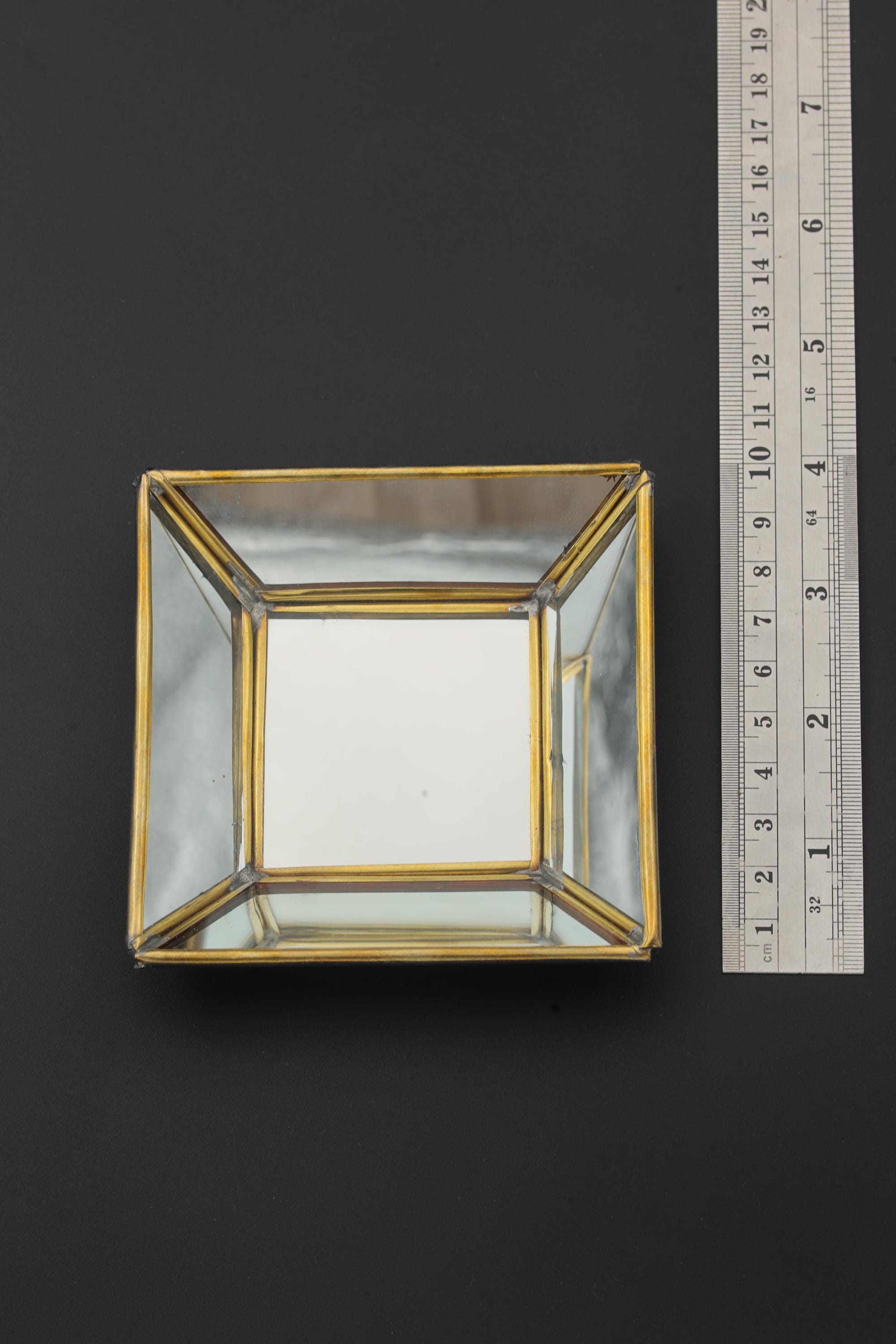 Brass mirror geometric tray shown beside a ruler for scale, with square reflective base and angled glass panels.