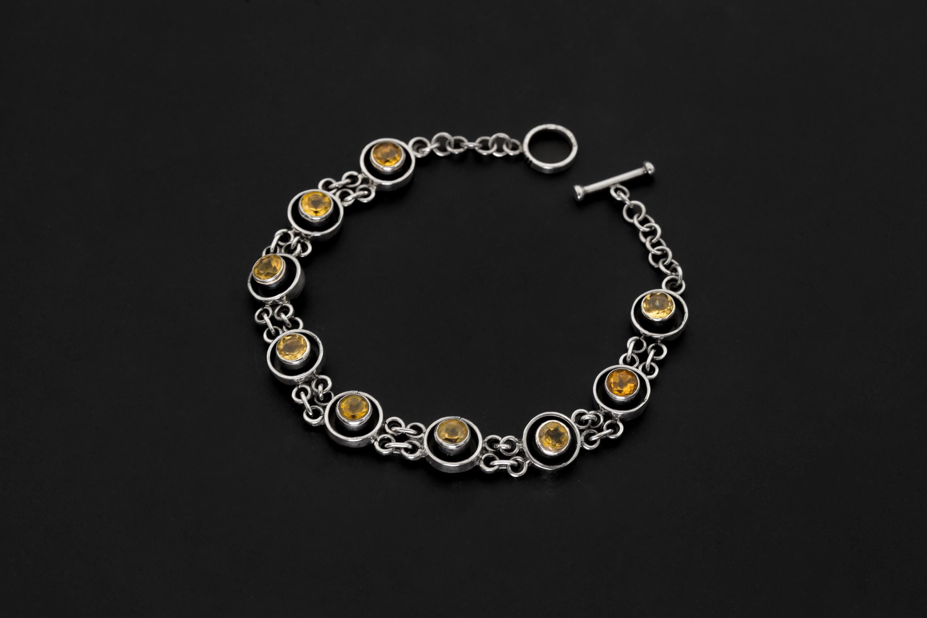 Citrine sterling silver bracelet displayed on dark background with golden faceted gemstones and toggle clasp.