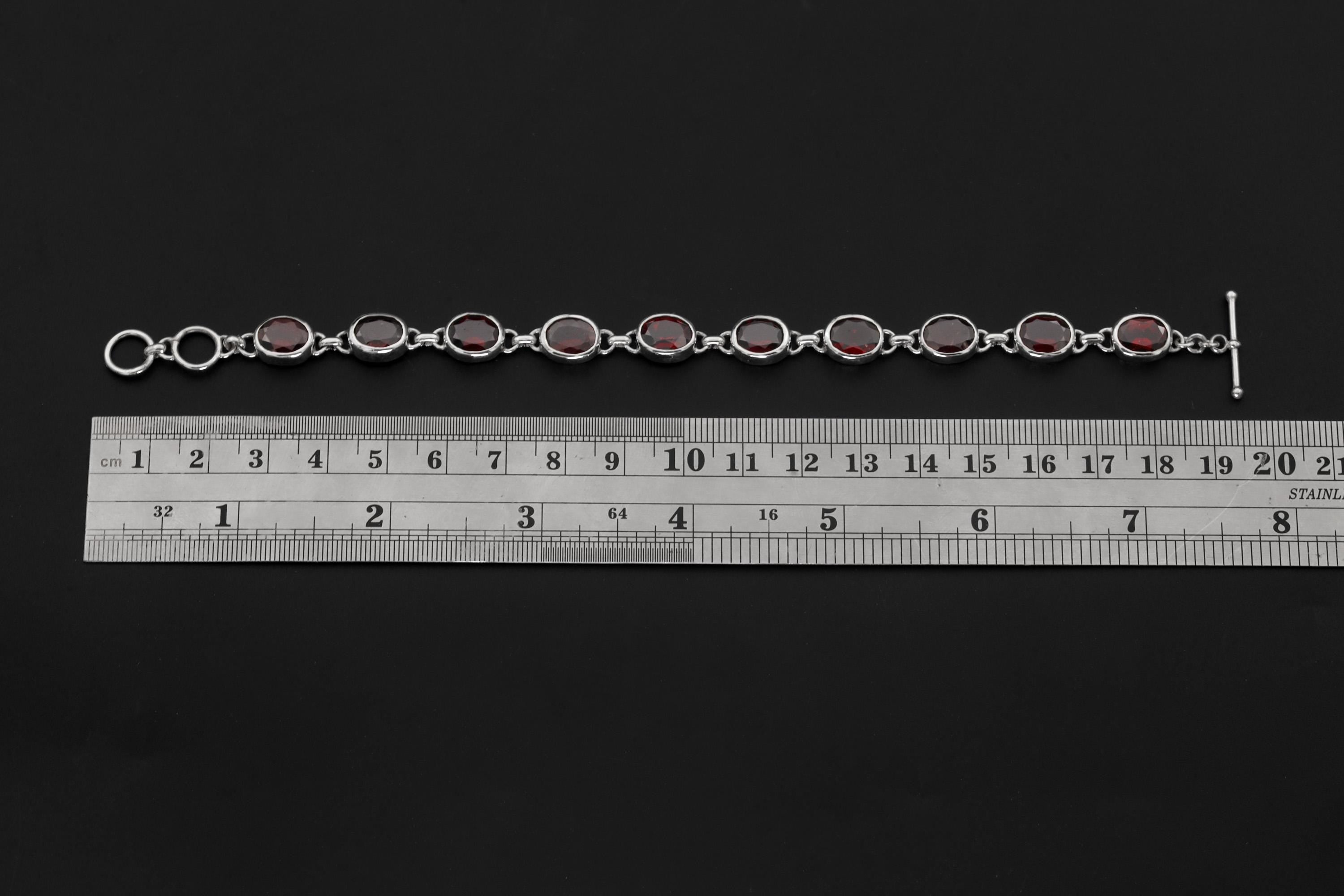 Garnet sterling silver bracelet shown beside a ruler for adjustable 18 to 20 cm length reference.