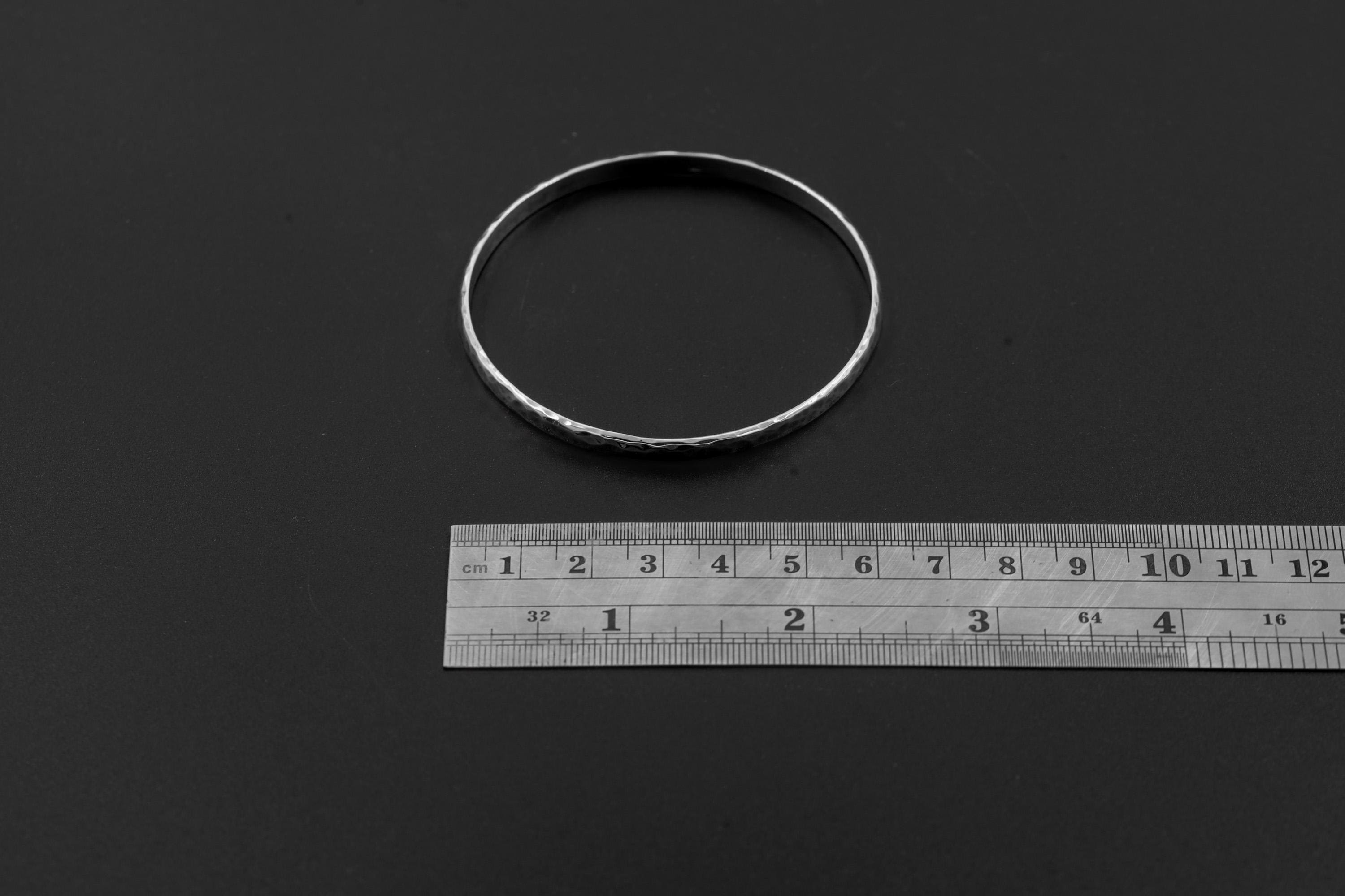 Hammered sterling silver bangle shown beside ruler for approximate size reference.