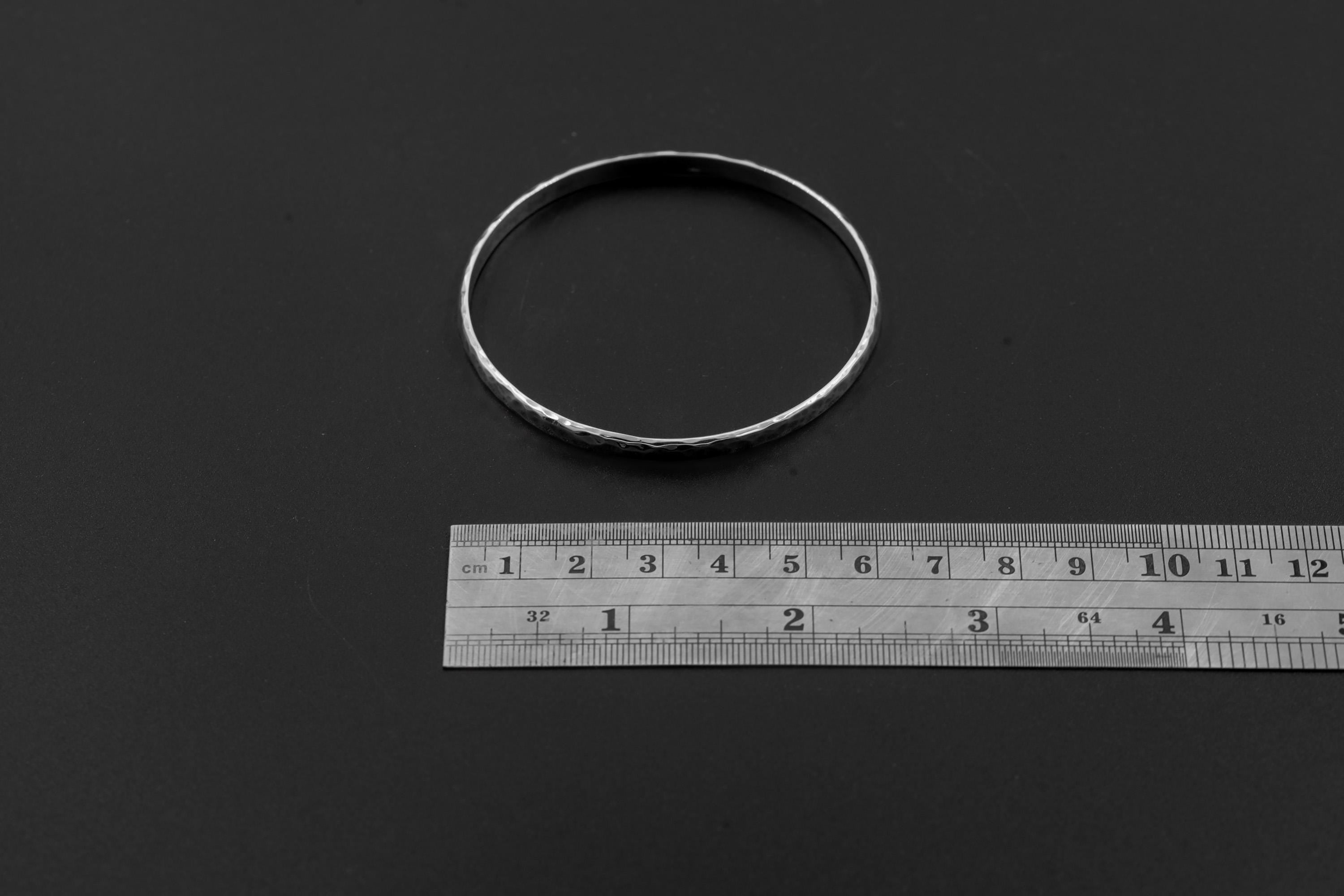 Hammered sterling silver bangle shown beside ruler for approximate size reference.