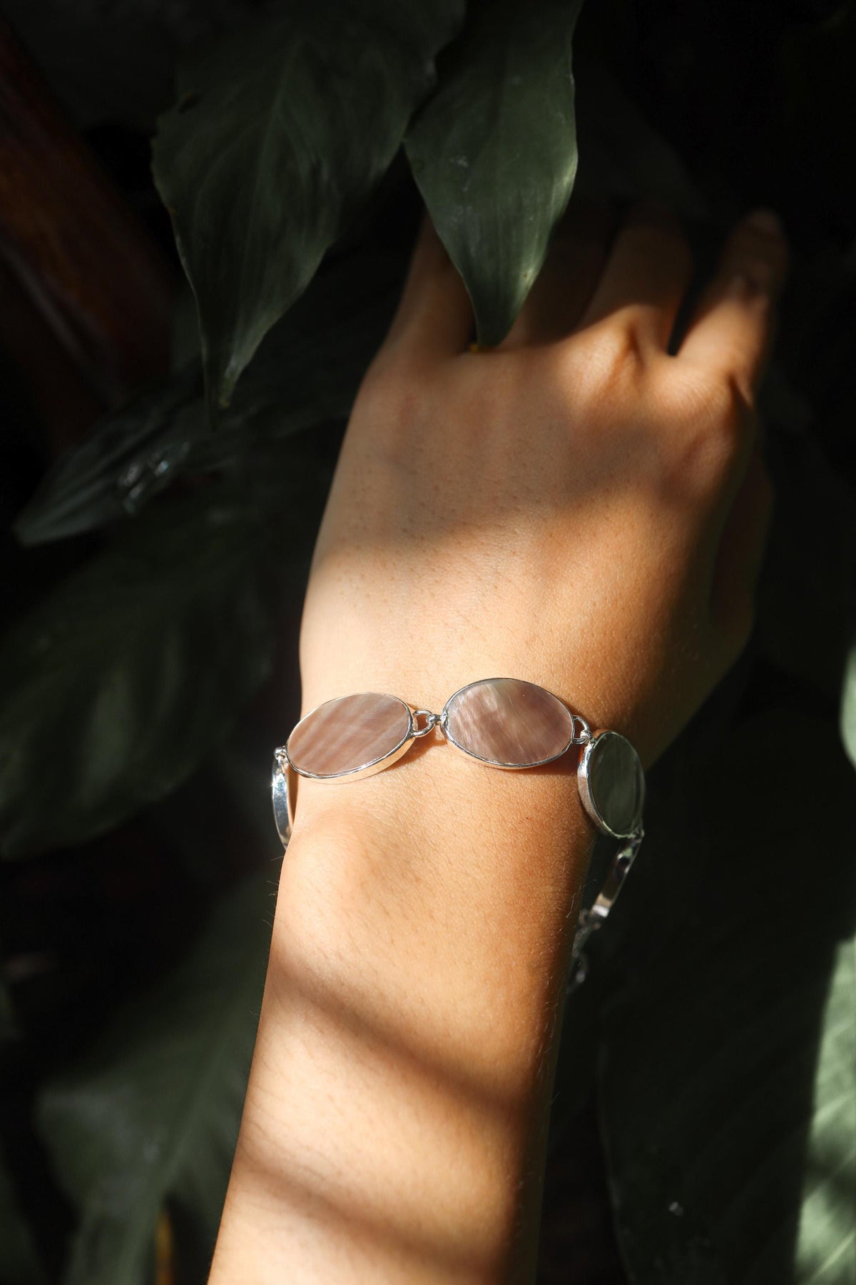 Mother of Pearl sterling silver bracelet shown worn on the wrist with soft oval shell cabochons.shadows.