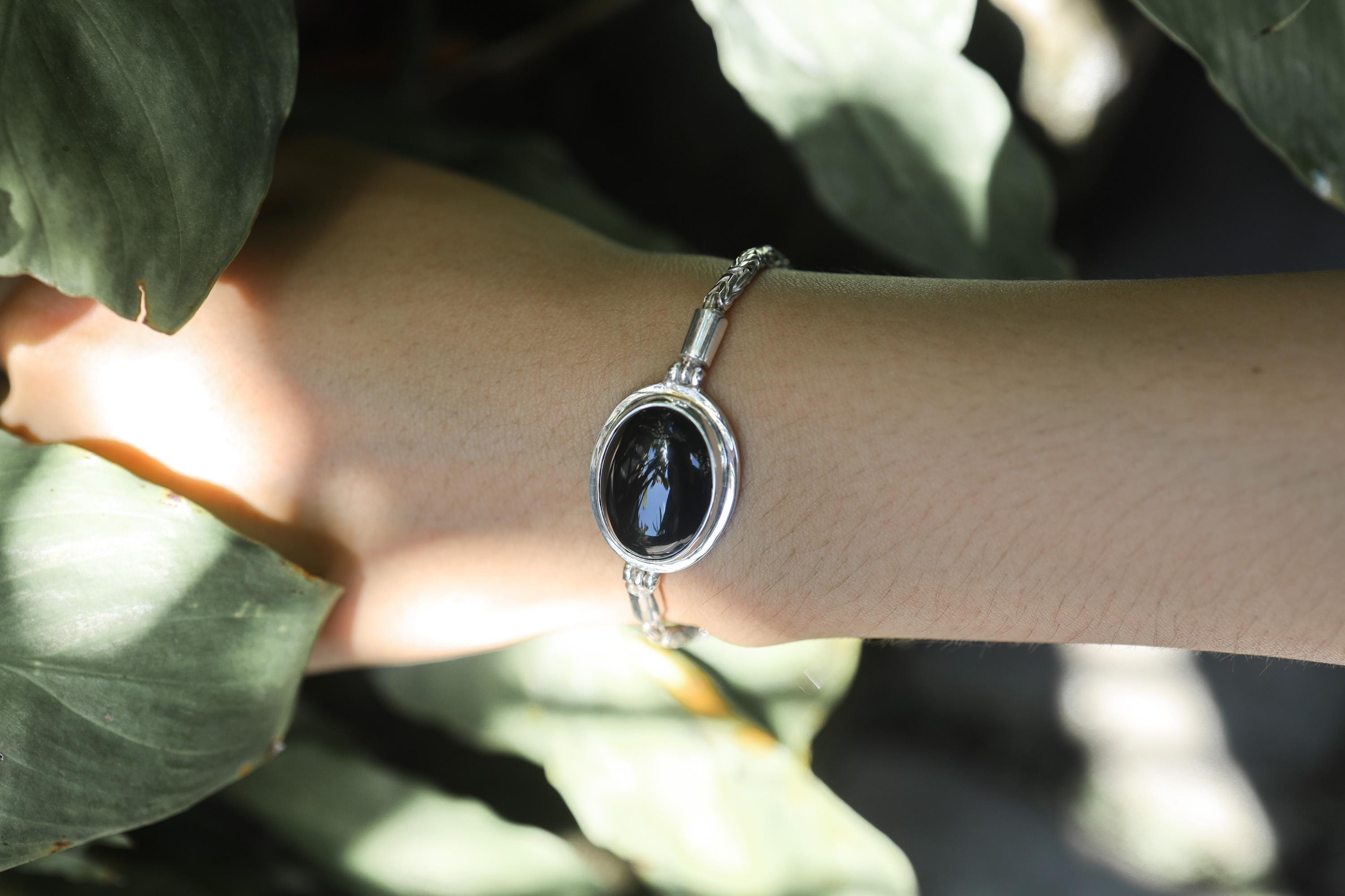 Black Onyx sterling silver bracelet shown worn on the wrist as a polished grounding gemstone piece.