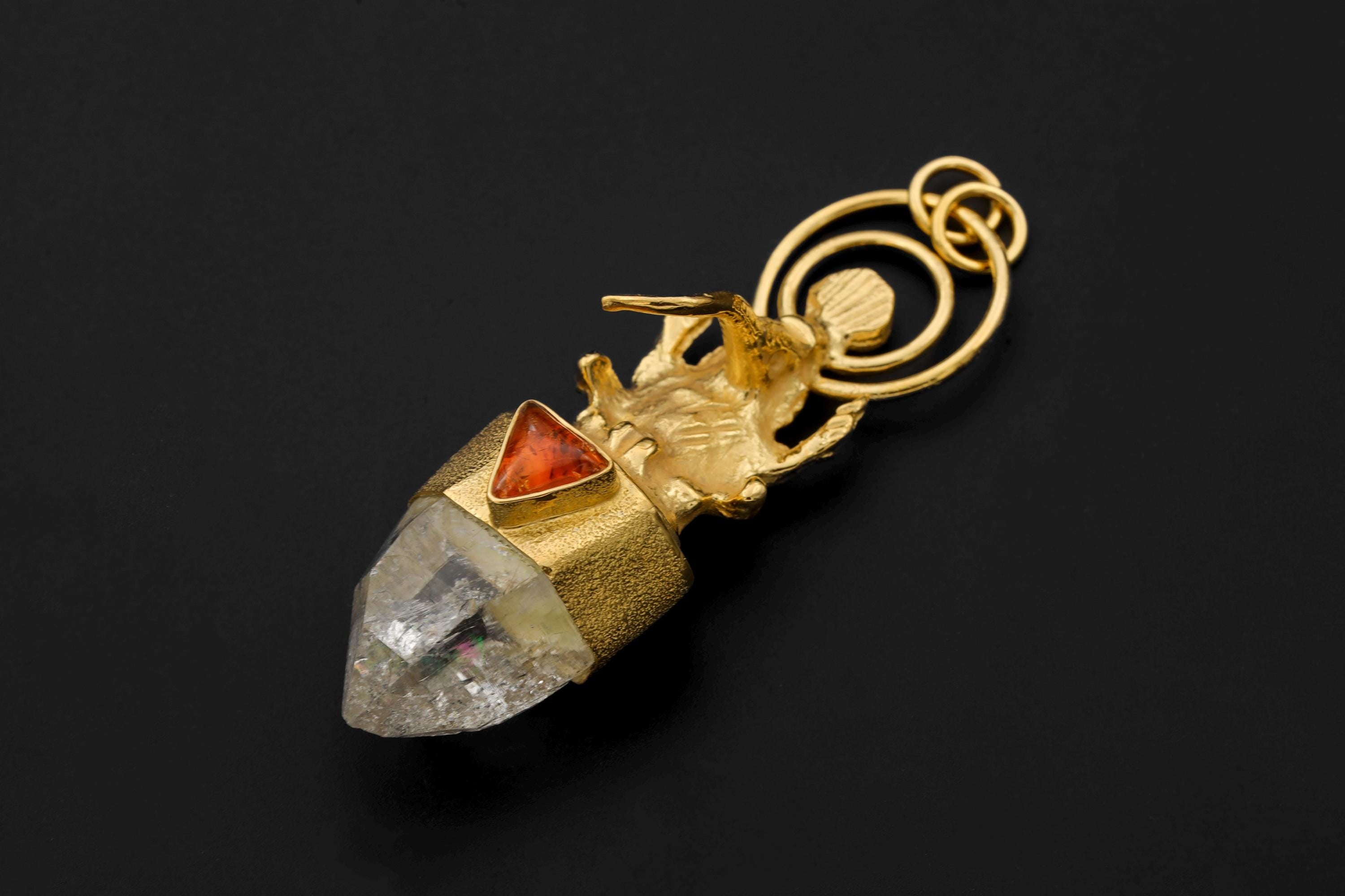 Pendant laid flat displaying the detailed Ganesha sculpture, spiral halo design, and faceted Lemurian Quartz termination.