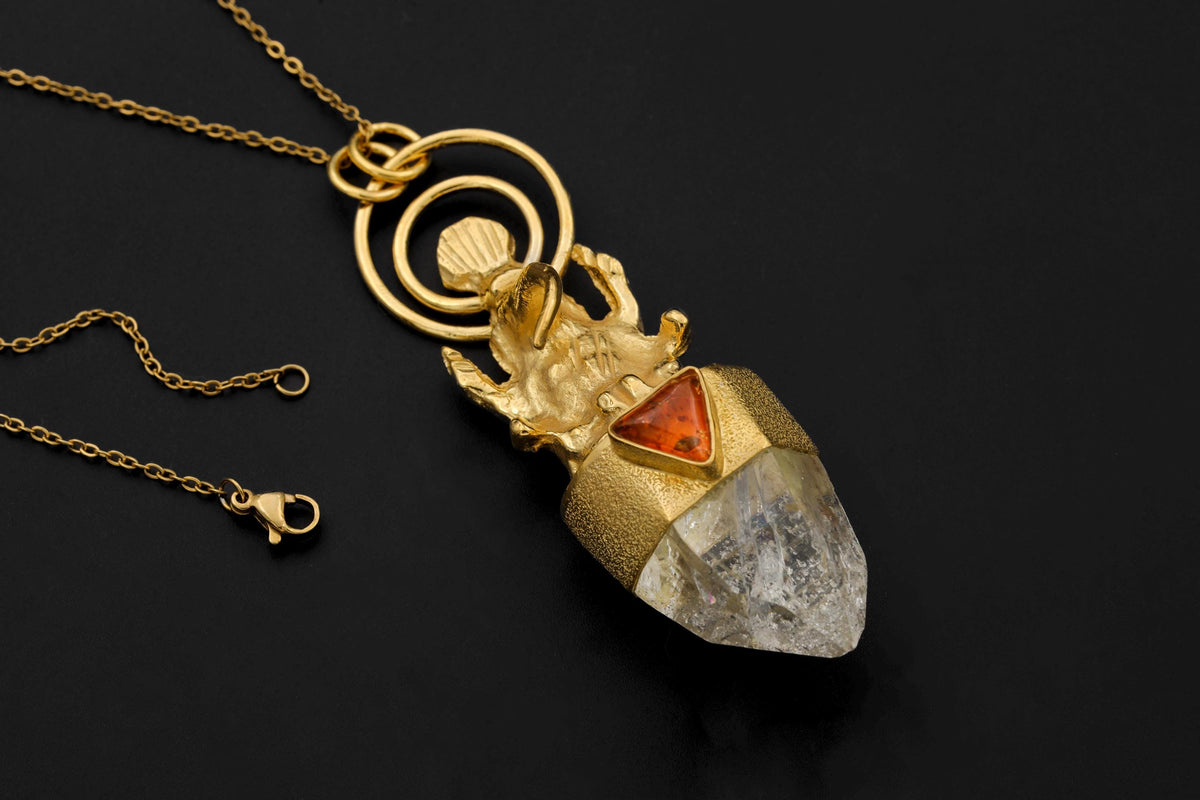 Lord Ganesha Amber Lemurian Quartz Talisman Pendant on black background featuring 18K gold-plated brass Ganesha figure above natural Baltic Amber triangle and Rainbow Pyrite Inclusion Quartz point.