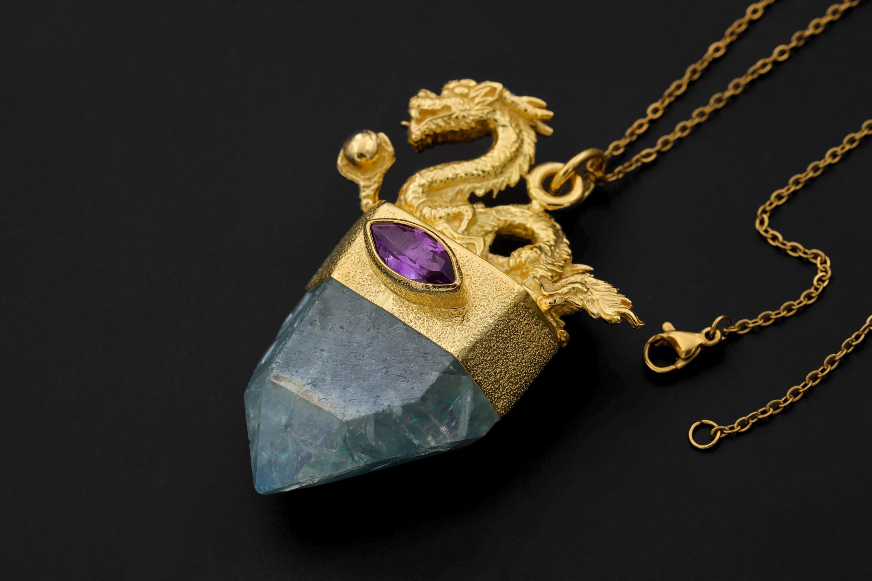 Dragon Amethyst Aqua Aura Quartz pendant shown on a dark background with 18k gold-plated brass crest and blue crystal point.
