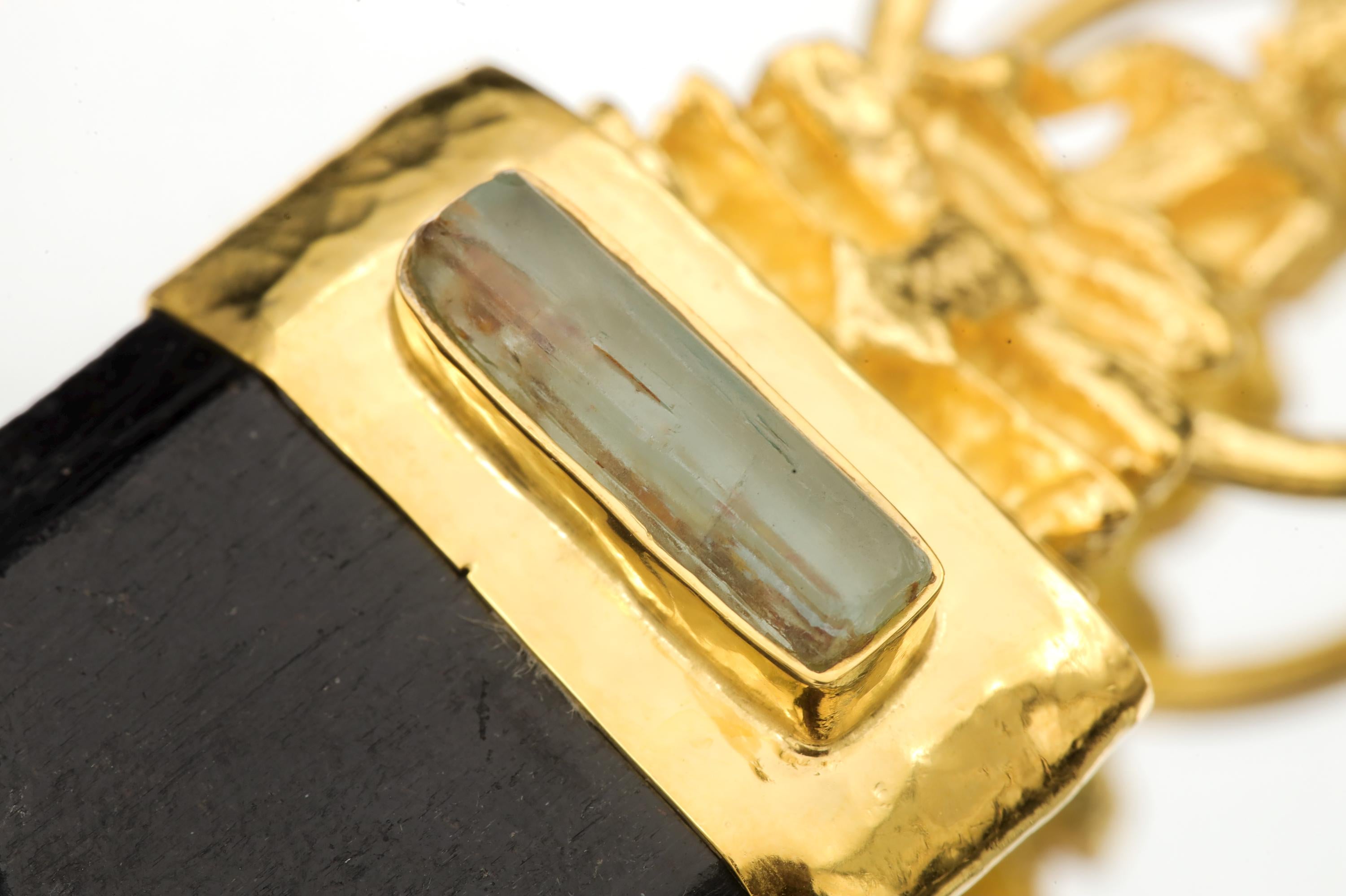 Close view of Buddha talisman pendant showing gold-plated figure, silver setting, and dark Black Tourmaline.