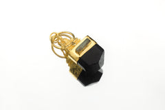 Pendant suspended against bright background showcasing reflective gold surfaces and quartz transparency.