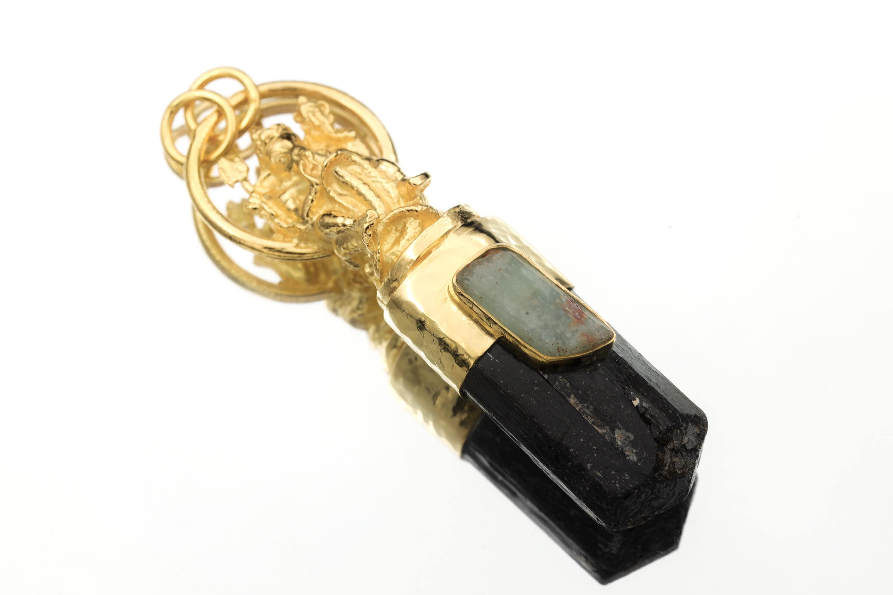 Close-up of aquamarine stone bezel revealing pale sea-blue tone, polished surface, and contrast against gold plating.