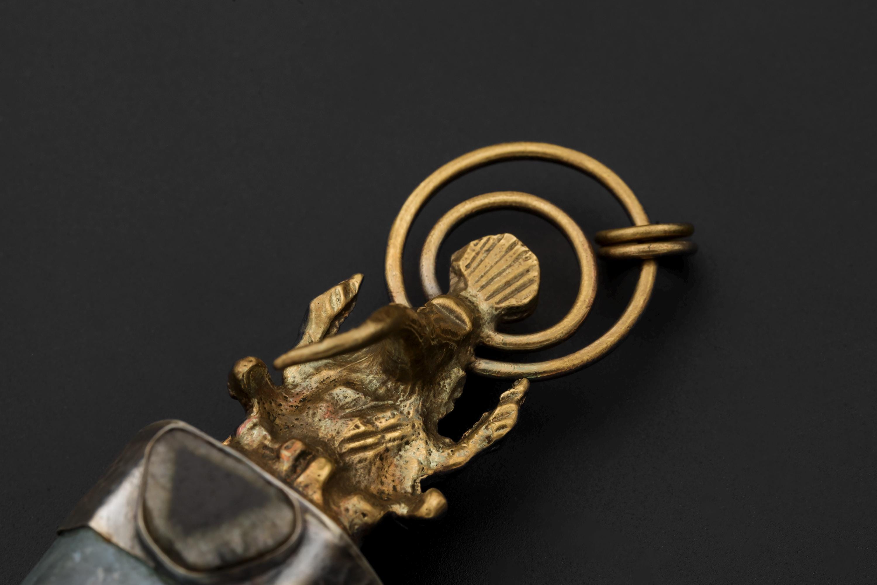 Close-up of brass loop bail and Ganesha detail on an Aqua Aura Quartz Blue Tourmaline spiritual pendant.