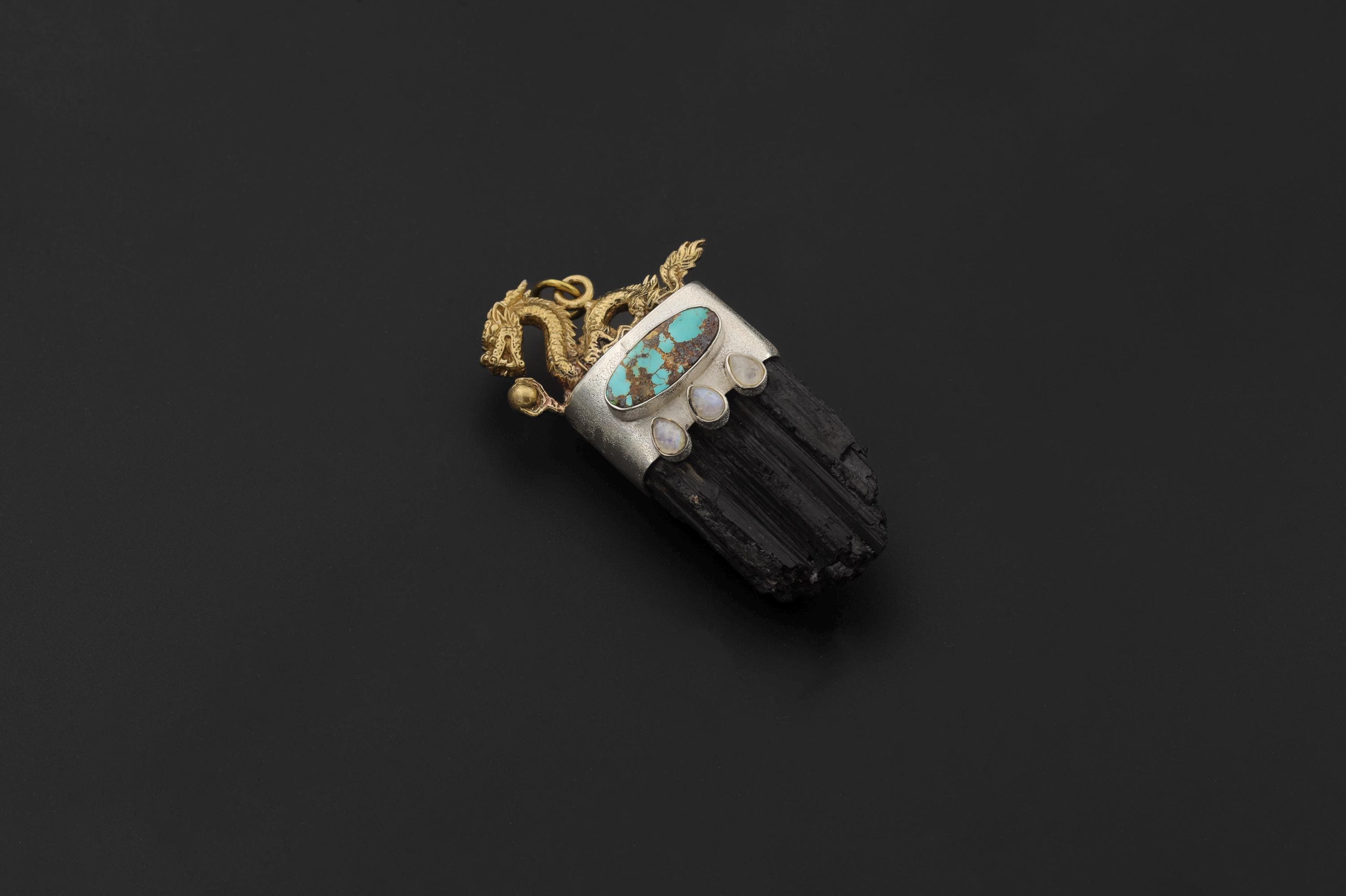Dragon Gold Brass Cast Talisman Pendant on black background showing detailed dragon figure above a chunky raw Black Tourmaline cluster with Sleeping Beauty Turquoise and Blue Moonstone cabochons set in silver bezel.