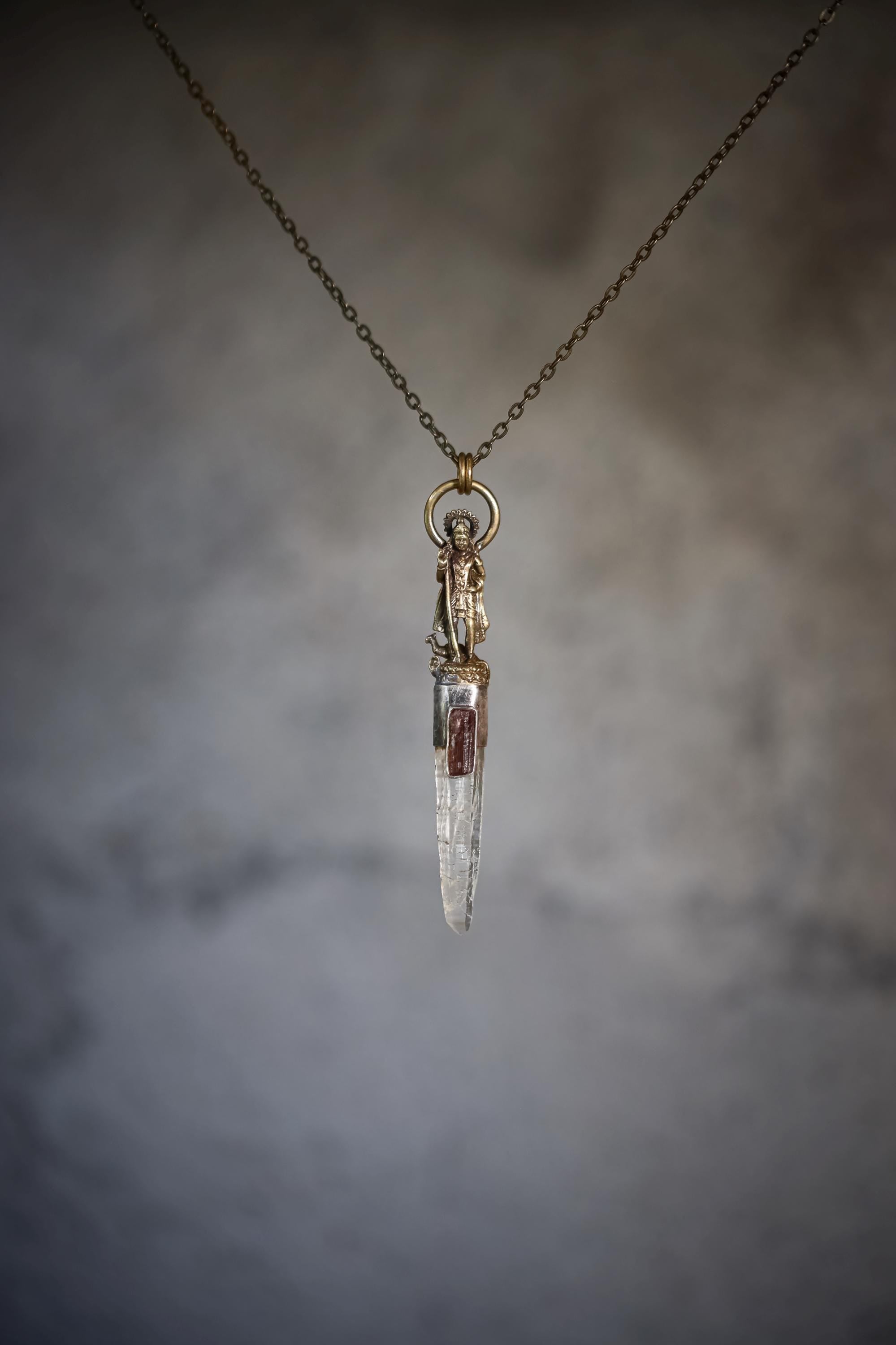 Pendant laid flat emphasizing oxidized patina and fine brass detailing of the Saraswati casting.