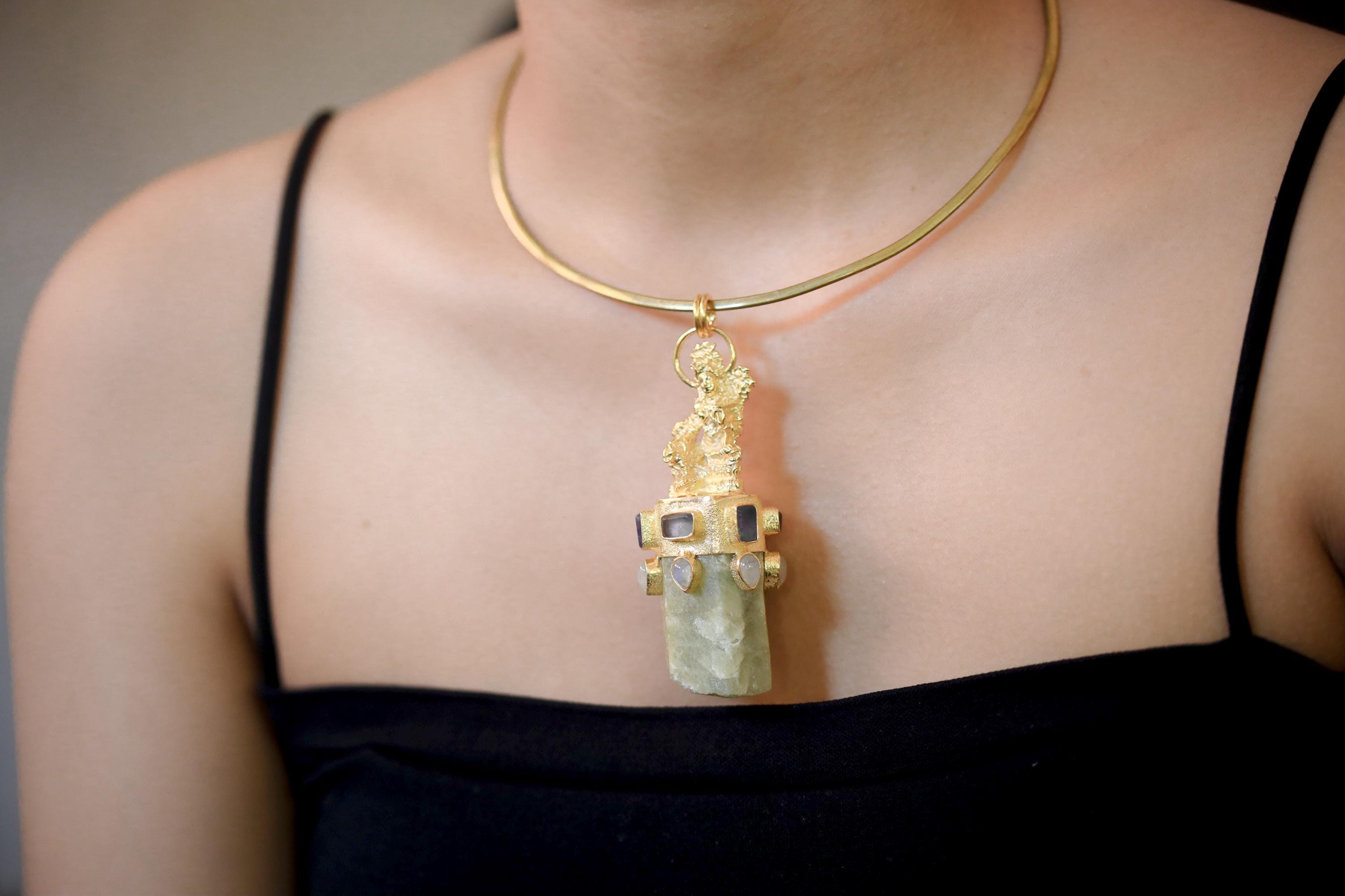 Pendant worn on model neckline under soft light showing dimensional depth and luxurious tone combination.