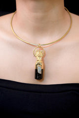Pendant worn on model chest showing full pendant length, gold sheen of Ganesha casting, and dark grounding tone of black tourmaline.