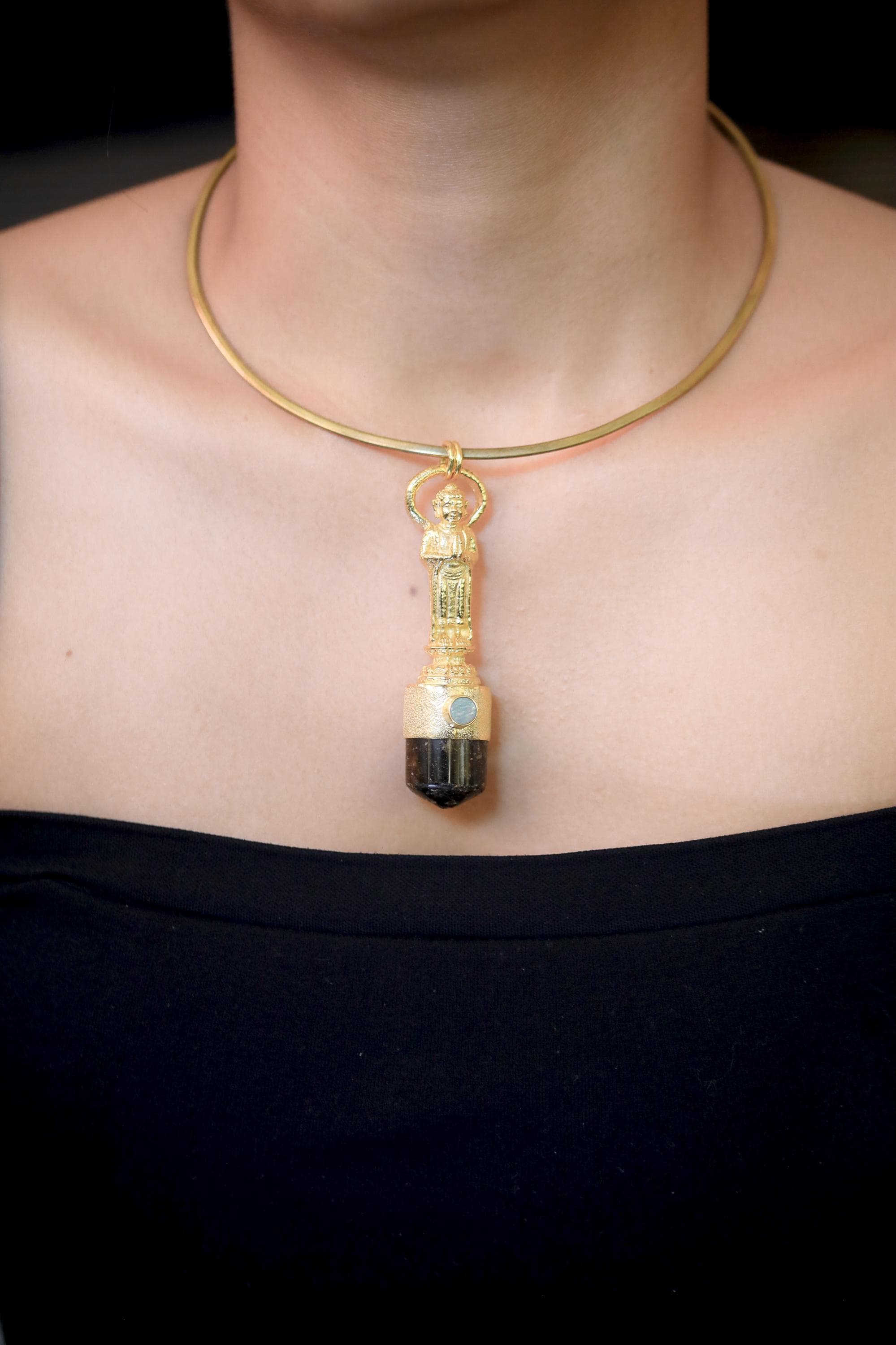 Pendant laid flat displaying symmetry between tourmaline point and round opal gem set within the sculpted top.