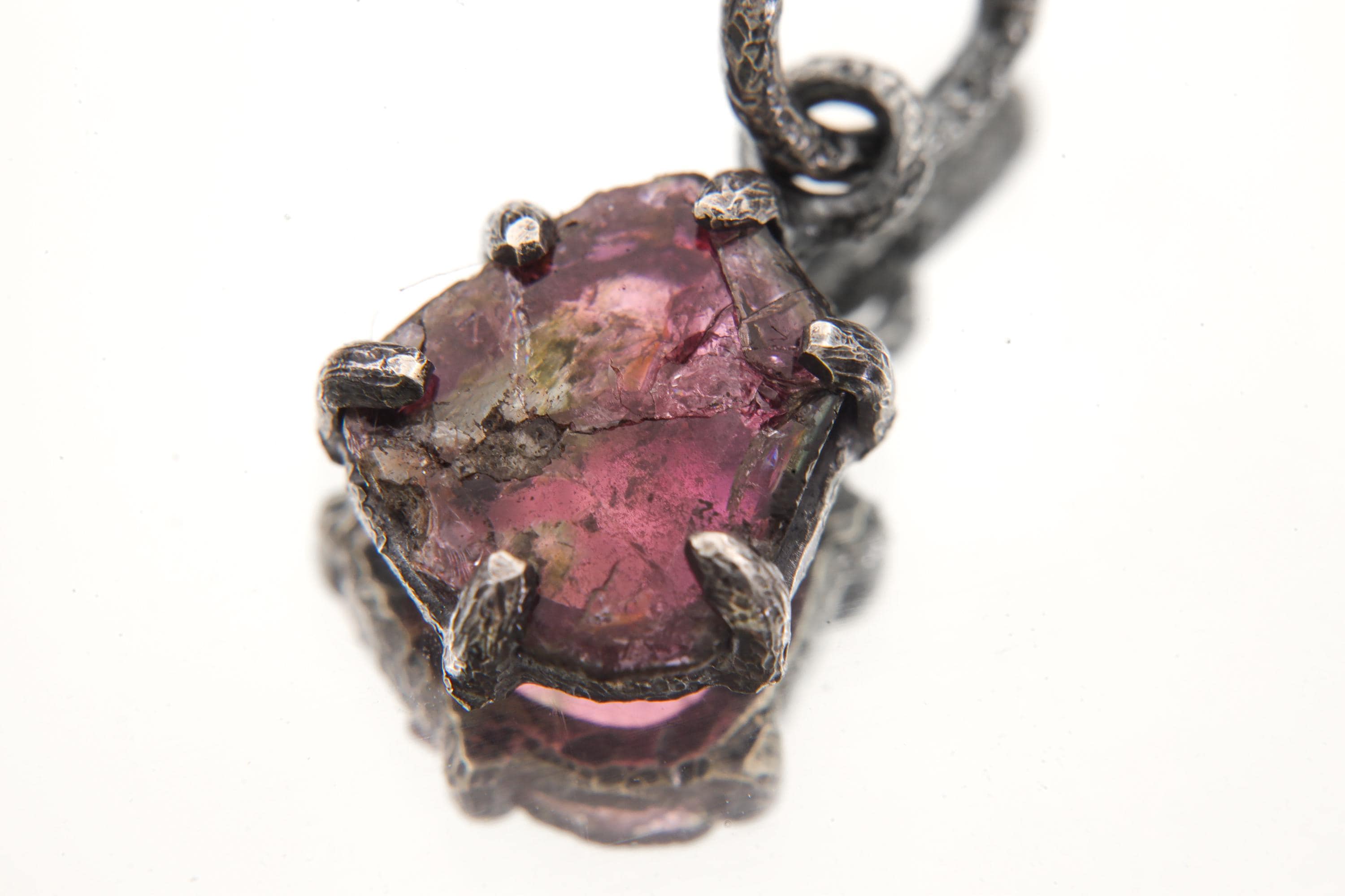 Pink Tourmaline Rubellite pendant on white background showing polished rose gemstone and rugged oxidized silver claws.