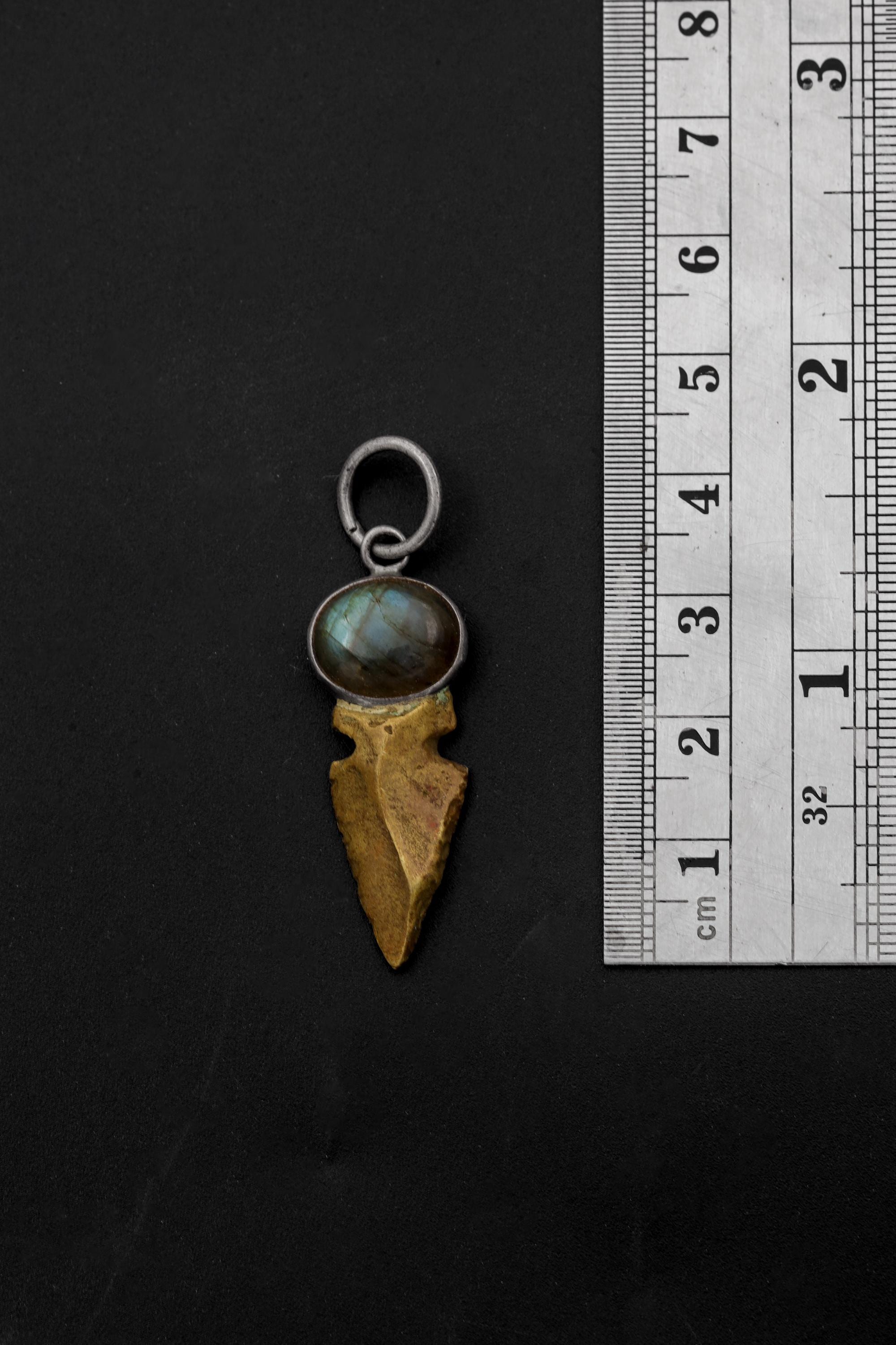 Labradorite Obsidian spearhead pendant shown beside ruler for approximate 5 cm size reference.