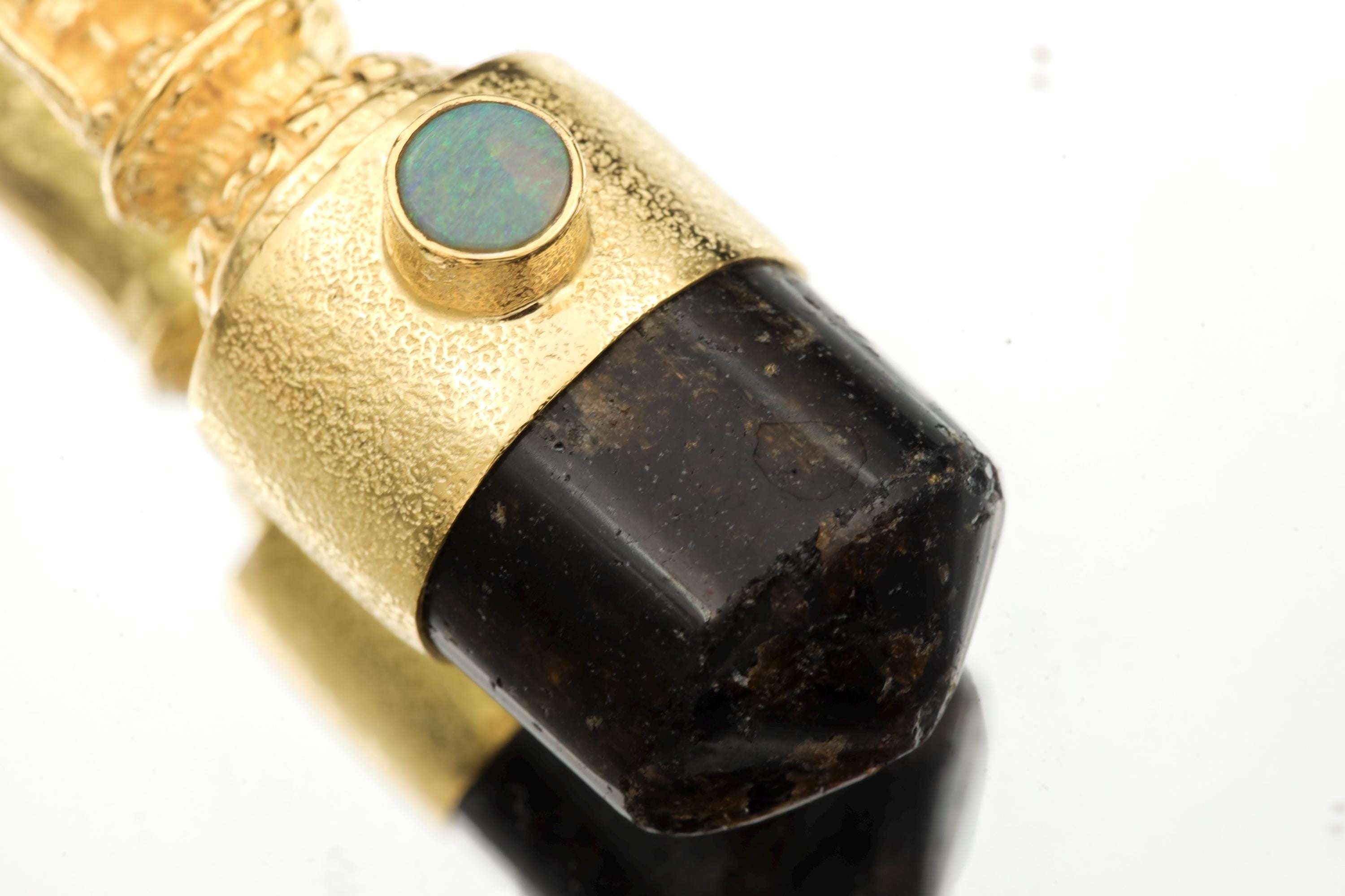 Close-up of Opal bezel revealing vibrant play-of-color with flashes of green, blue, and orange against matte gold surface.