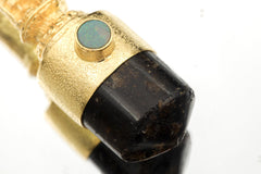 Close-up of Opal bezel revealing vibrant play-of-color with flashes of green, blue, and orange against matte gold surface.