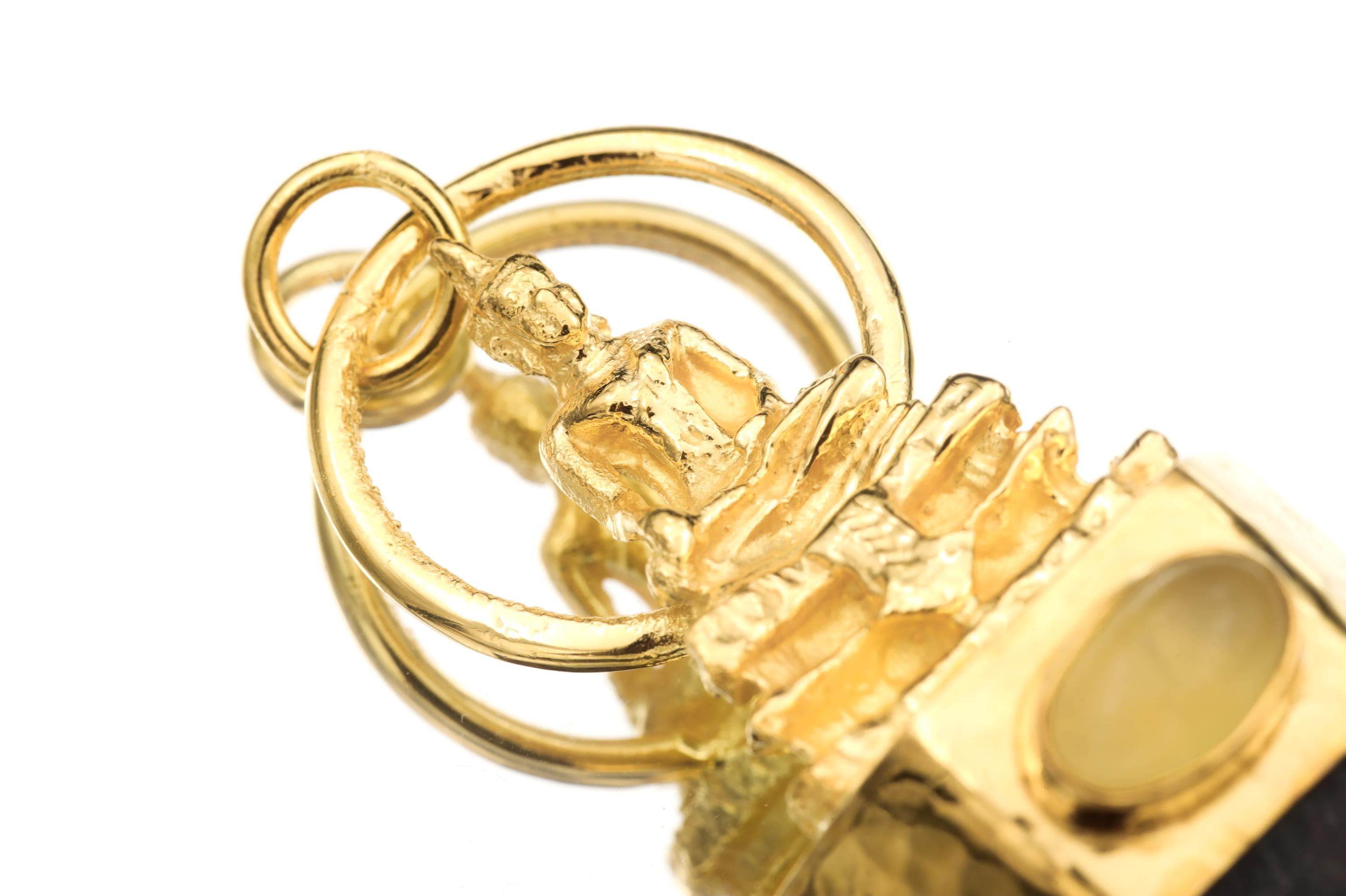 Macro photo capturing opal’s iridescent play-of-color and fine hammered texture on gold bezel