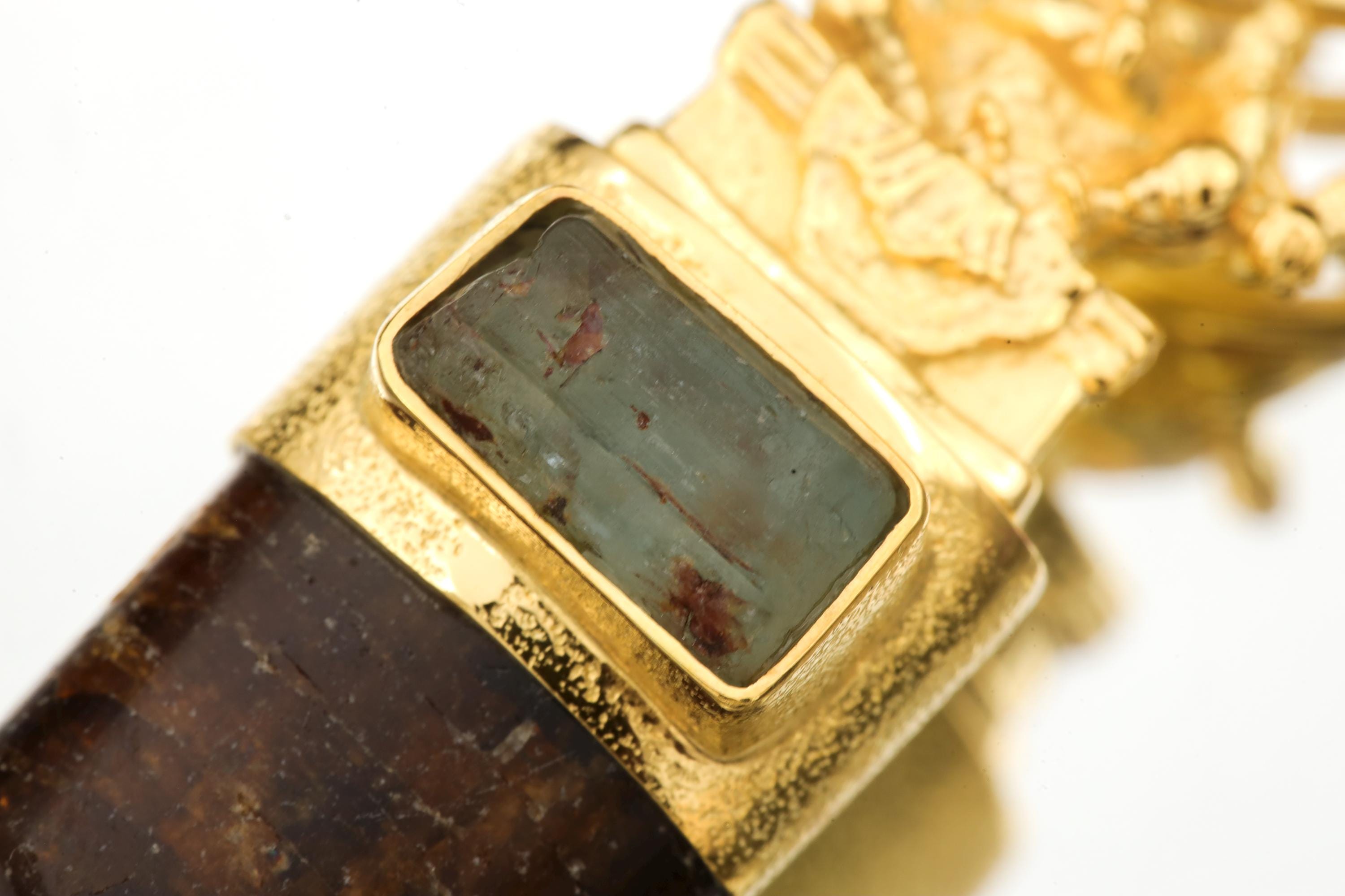 Close-up of square Australian Aquamarine Wand set beneath a gold-plated Ganesha figure in hammered silver bezel.