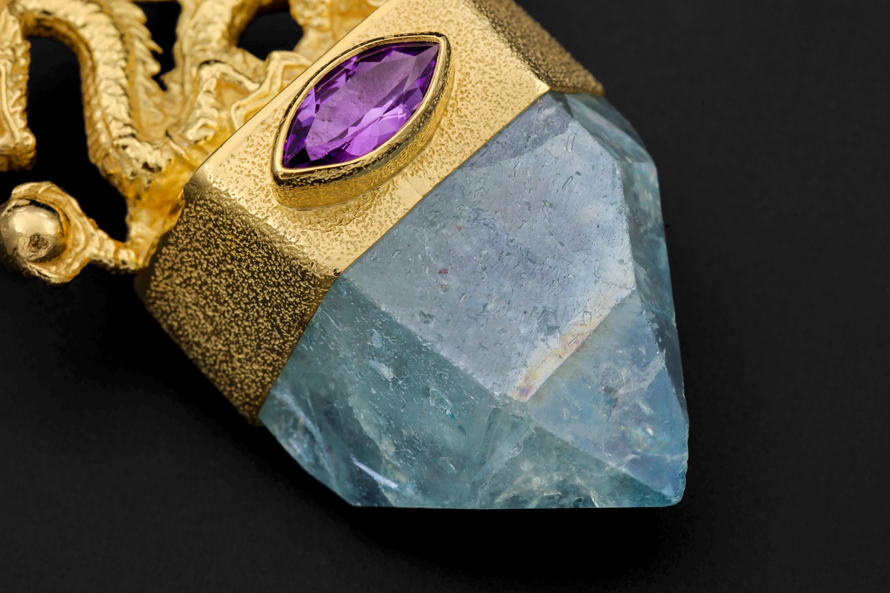 Close-up of dragon casting showing fine scales, curling tail, and high-shine gold finish over textured metal.