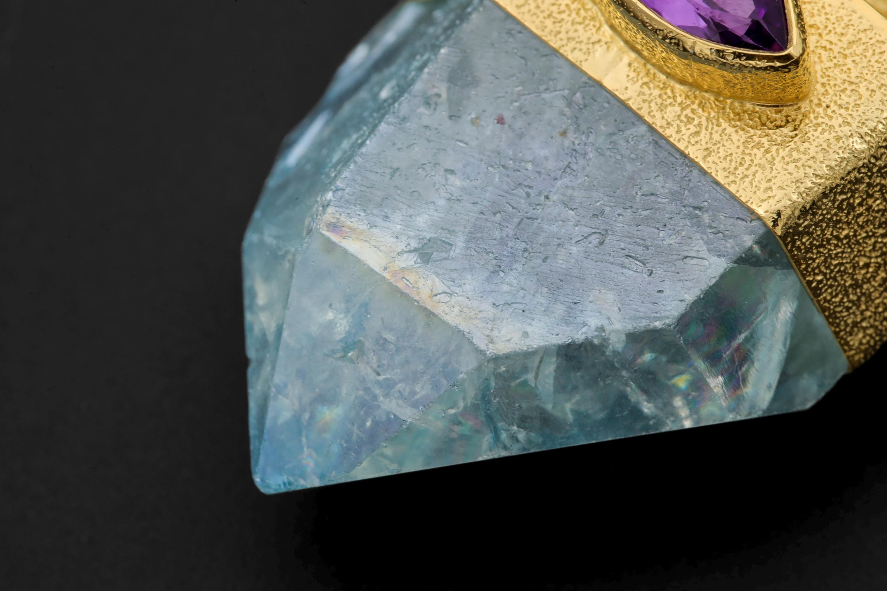 Close-up of Aqua Aura Quartz Point beneath a dragon Amethyst talisman, showing blue iridescent crystal surface.