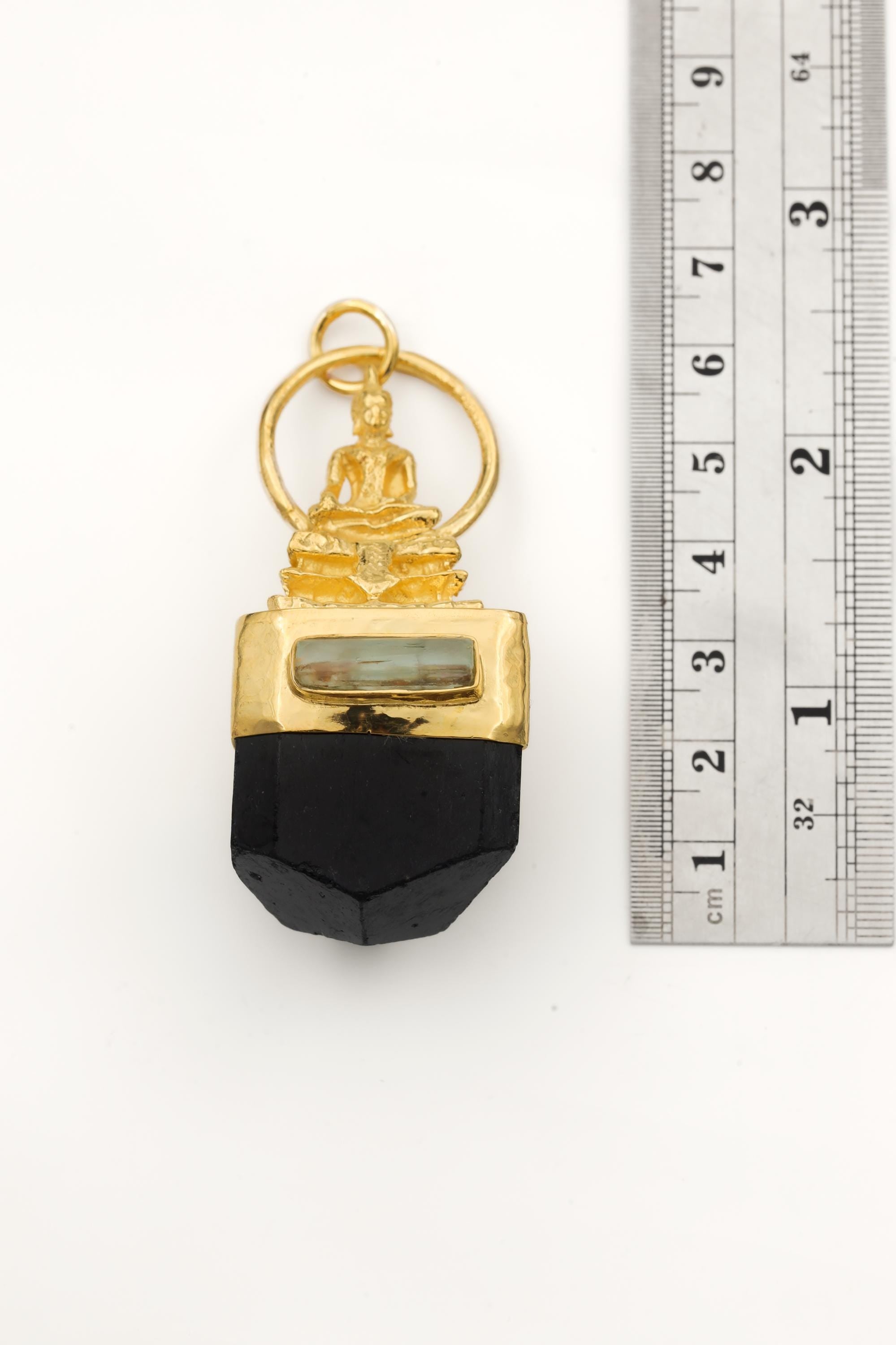 Close view of Buddha talisman pendant showing gold-plated figure, silver setting, and dark Black Tourmaline.