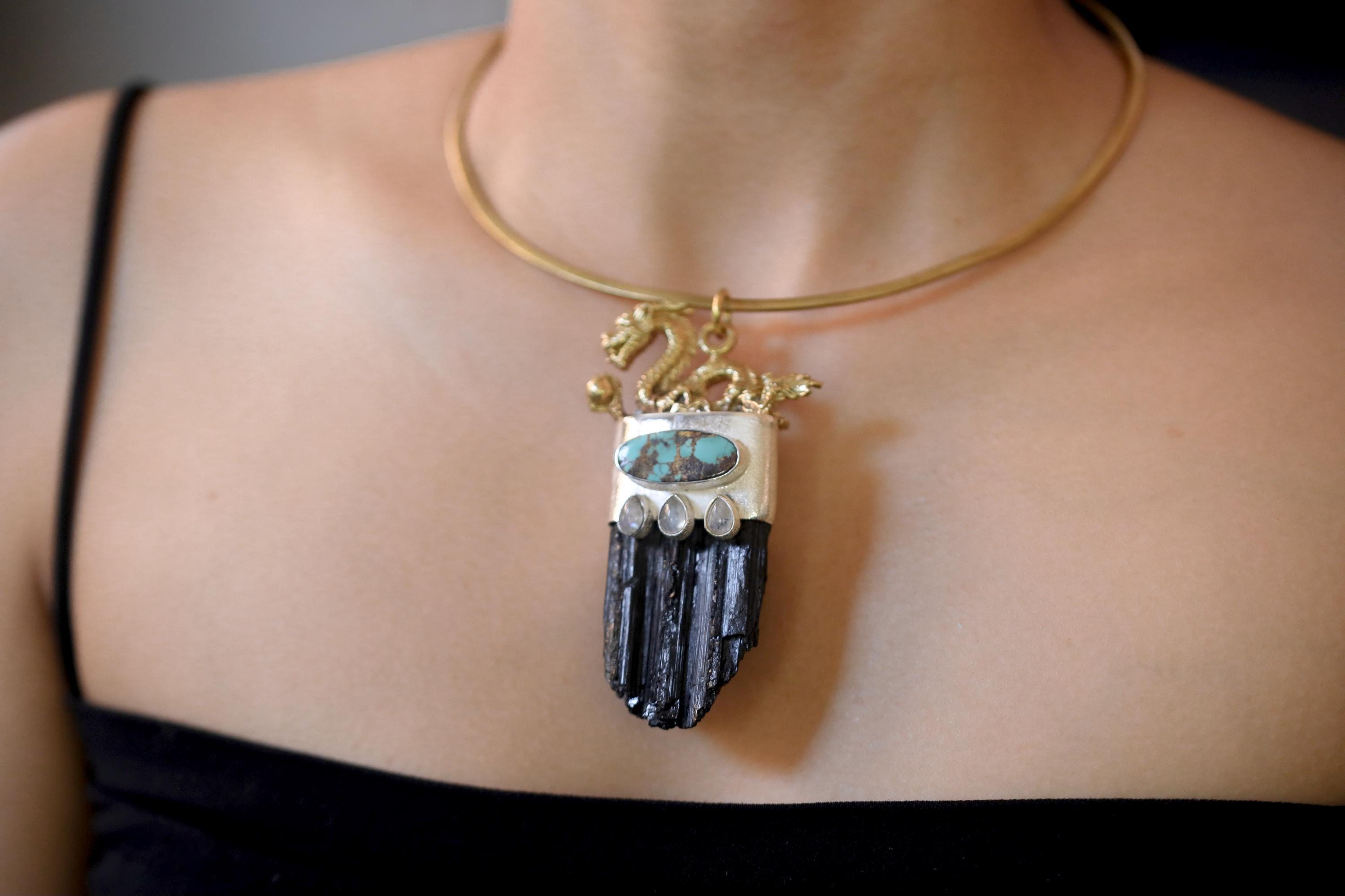 Pendant flat lay with black tourmaline texture visible alongside dragon motif details.