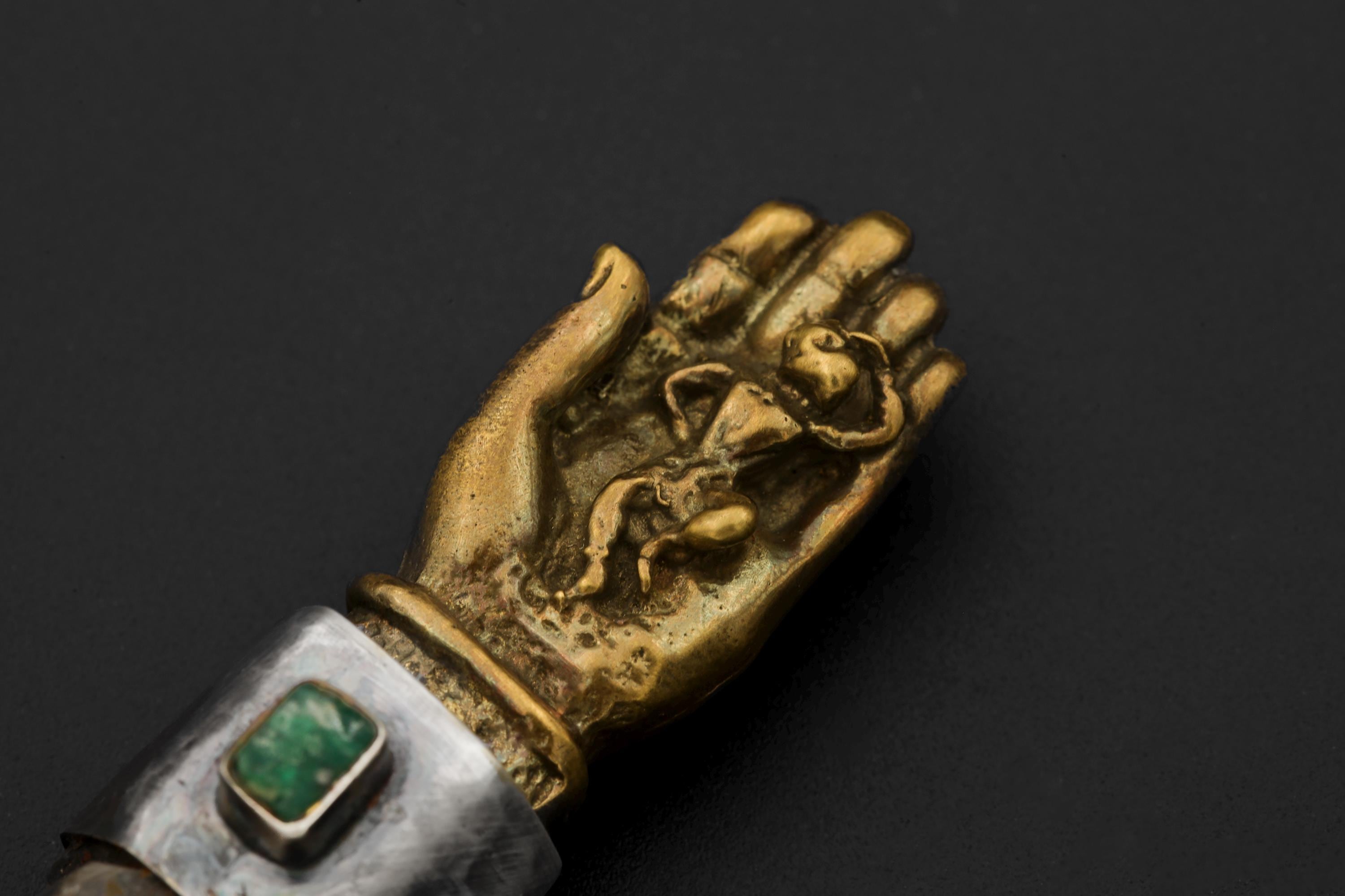 Overhead image focusing on alignment of Buddha hand design, natural chlorite phantoms inside quartz, and square-cut emerald cabochon.