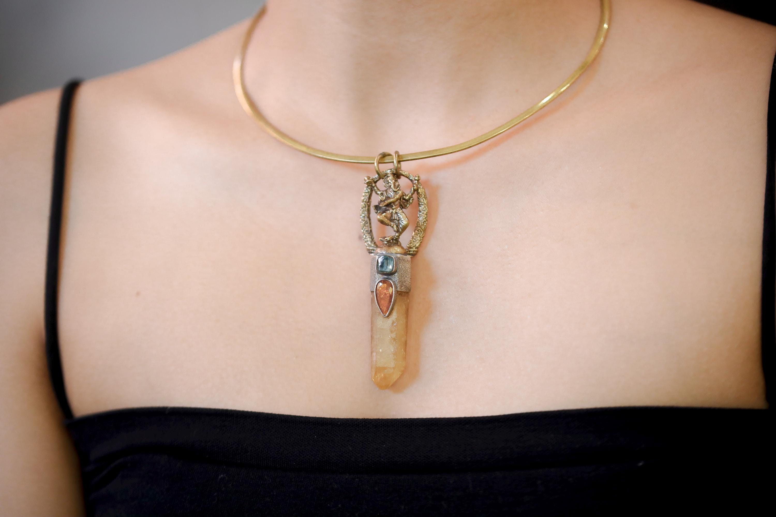 Pendant on model neckline in natural light revealing how gold and silver tones complement warm and cool gemstones.