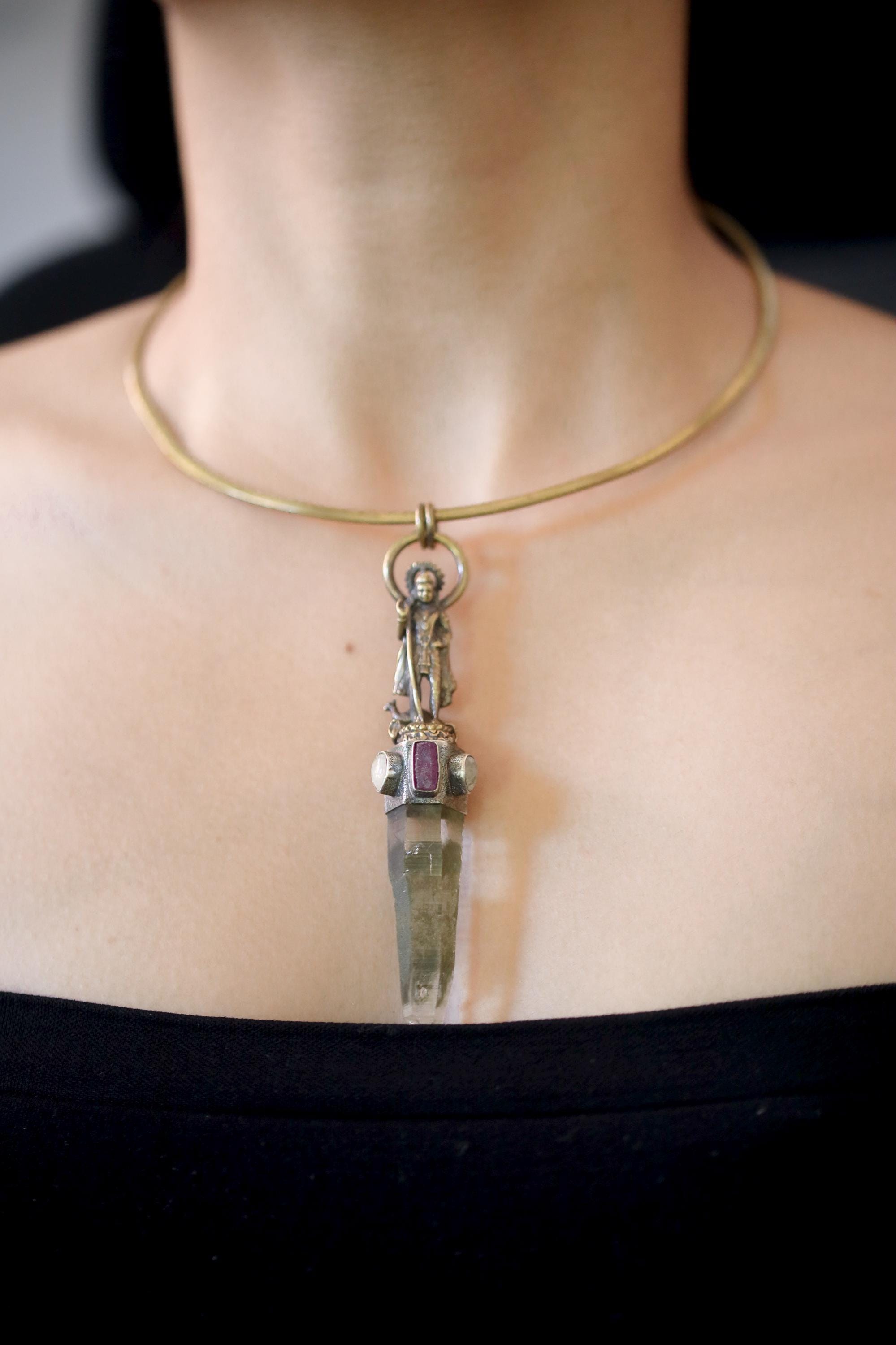 Pendant worn on model chest showing full length and proportion, reflecting metallic tones under natural light.