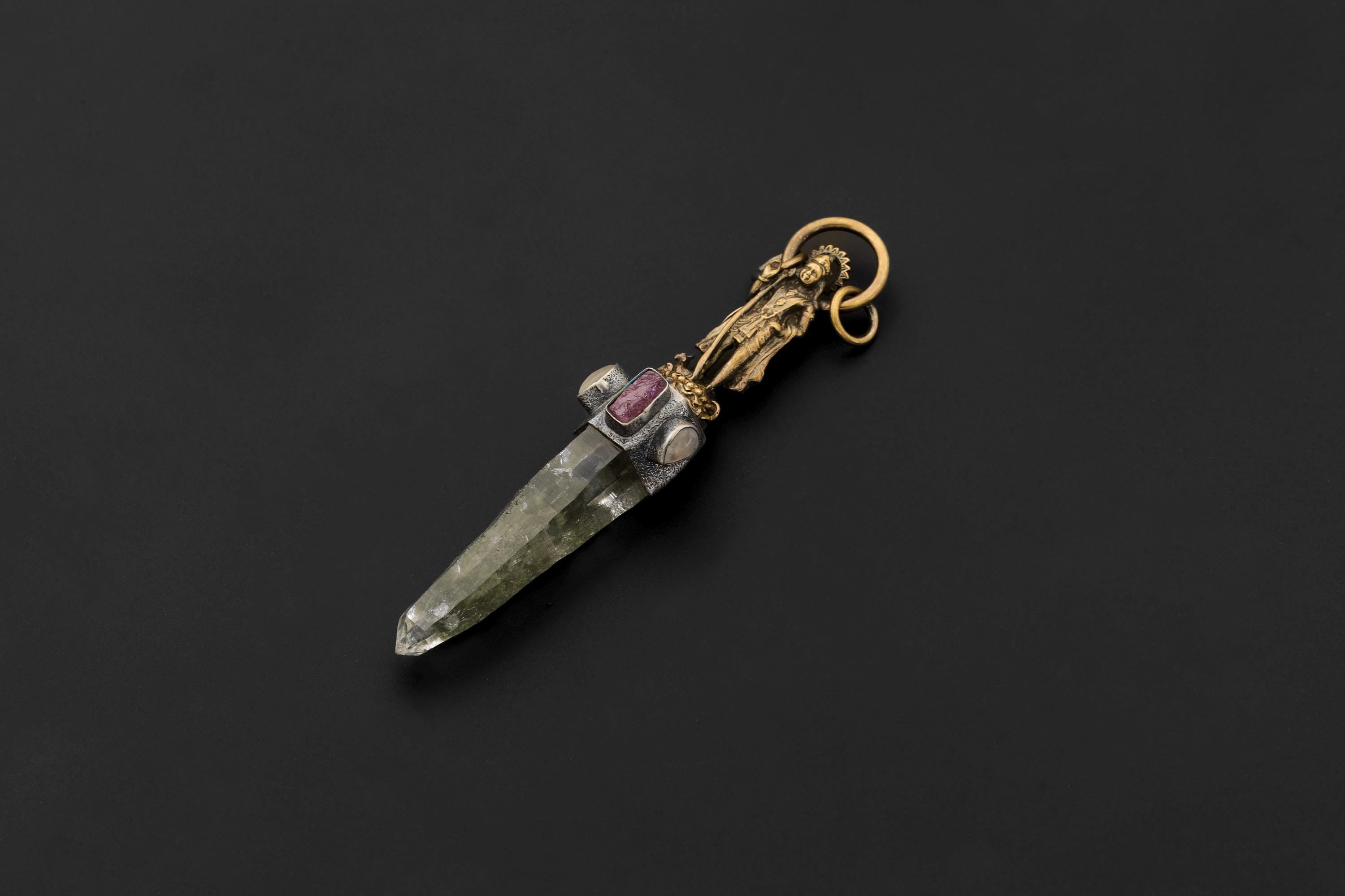 Pendant viewed from angle emphasizing Saraswati figure detailing and fine metal texture.
