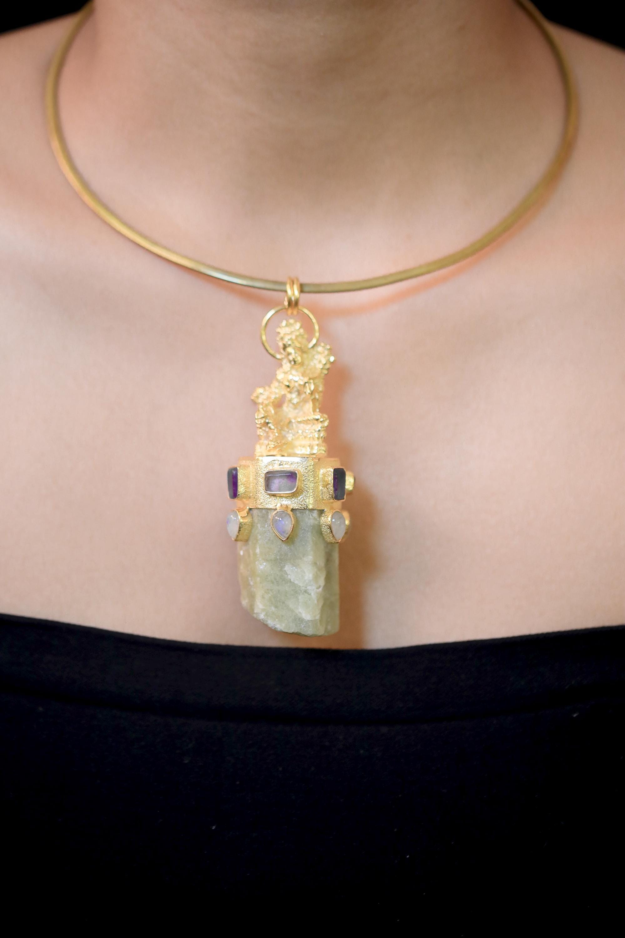 Pendant laid flat illustrating gold-brass casting detail, oxidized silver bezel contrast, and stone alignment.