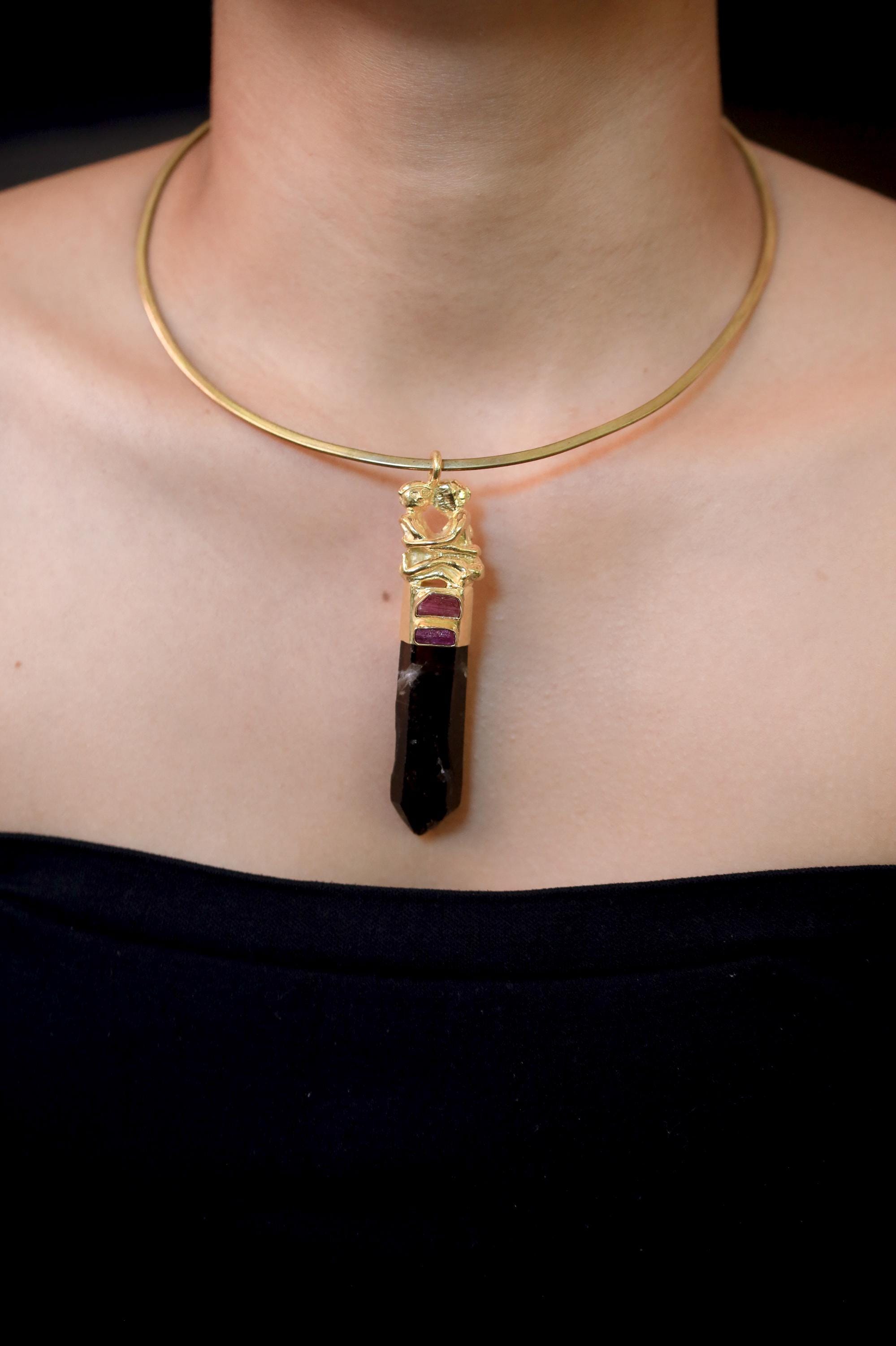 Pendant on model neckline under natural light emphasizing earthy tones and metallic contrast.