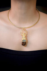 Lord Ganesha Talisman Pendant on white background featuring intricate gold-plated brass Ganesha figure above natural Brown Dravite Tourmaline crystal and square-cut Aquamarine set in 925 sterling silver bezel.