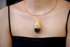 Pendant worn on model chest showing full pendant length, reflective gold plating, and deep smoky tone of quartz crystal