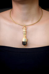 Pendant worn on model chest showing pendant length, golden sheen, and deep brown tone of Dravite Tourmaline under soft light.