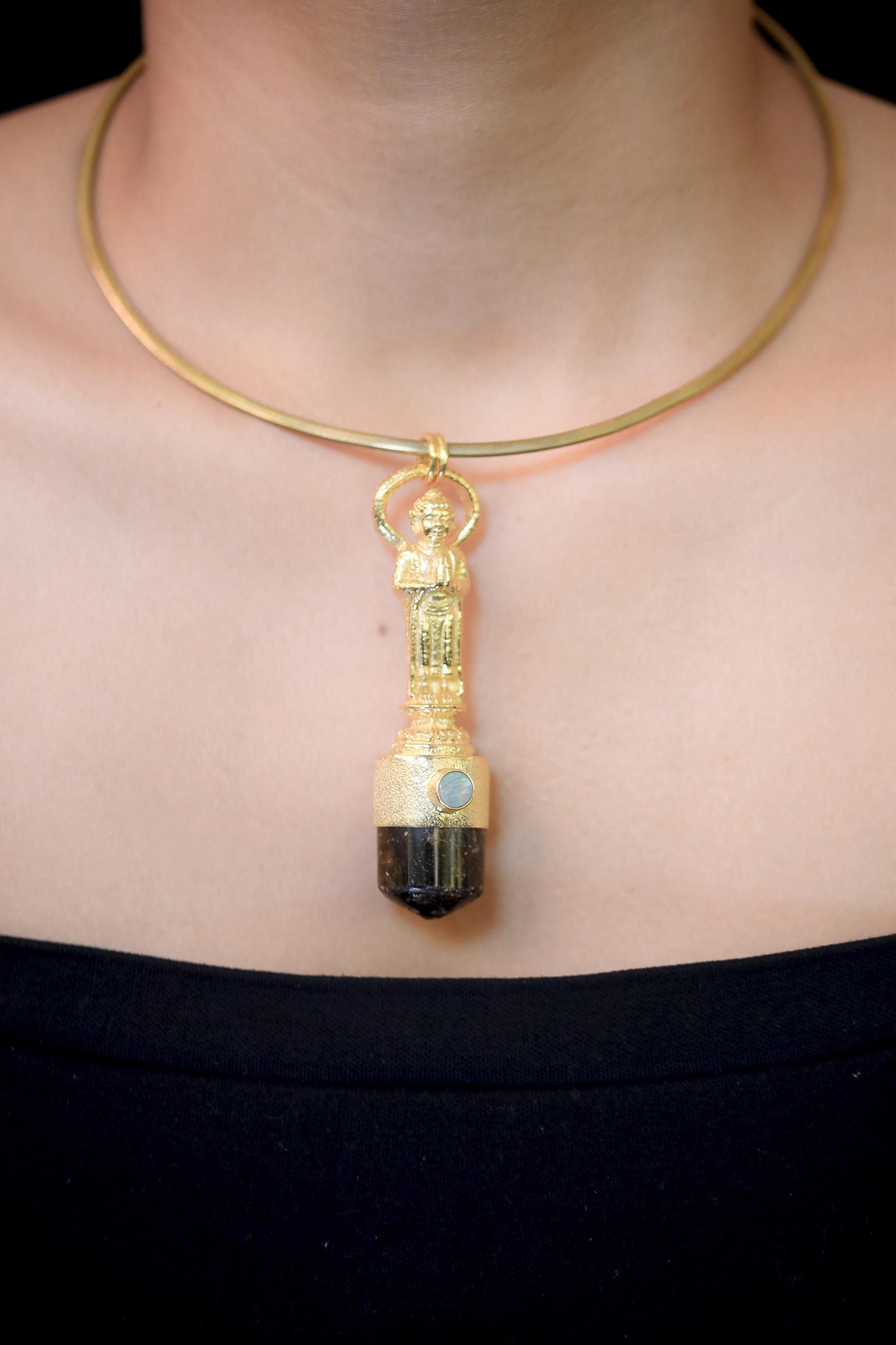 Pendant on model neckline under neutral light showing how gold, brown, and opal tones complement skin tone.