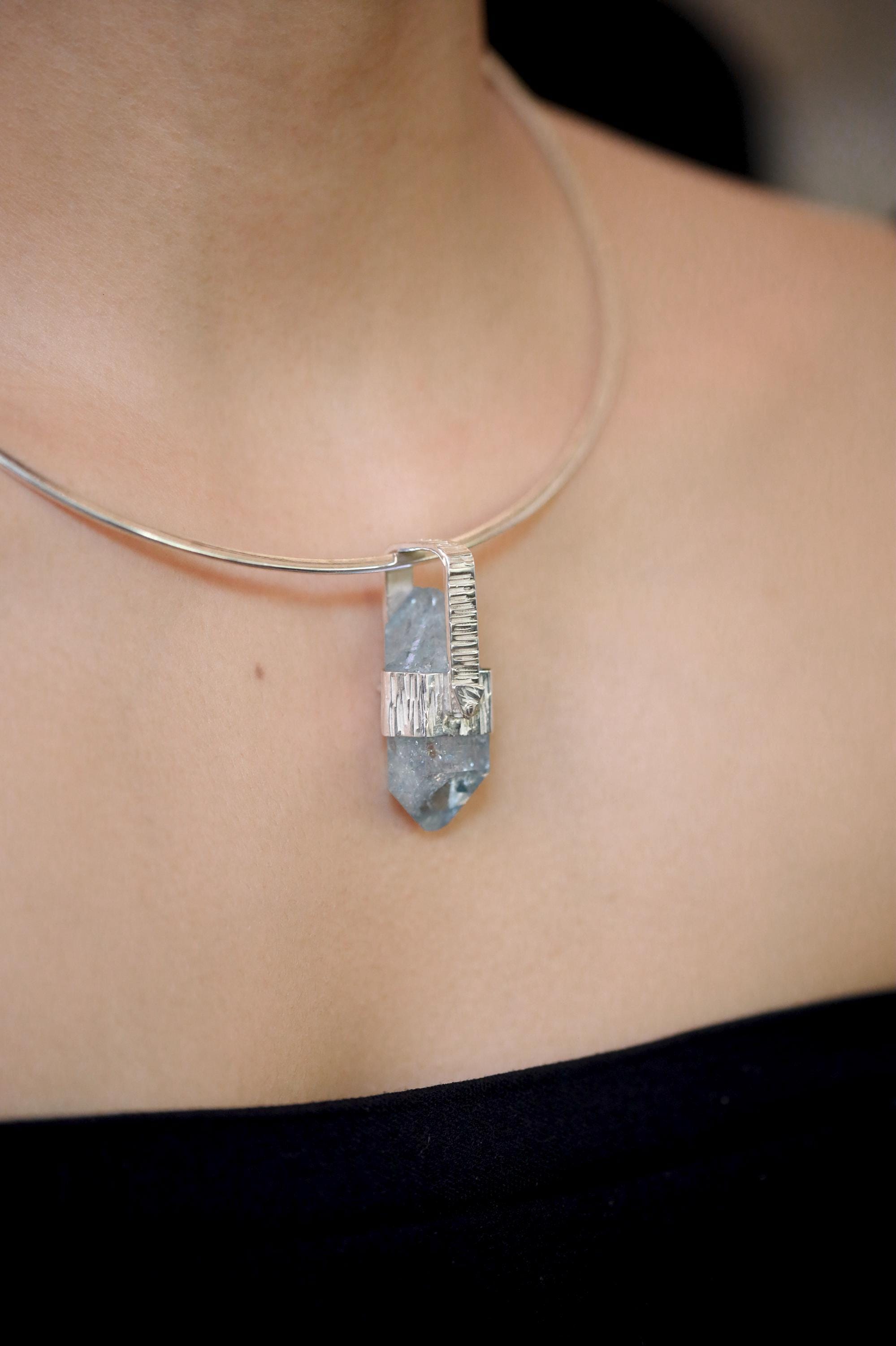 Aqua Aura Quartz pendant shown worn on a model, with high-shine sterling silver setting and blue crystal point.