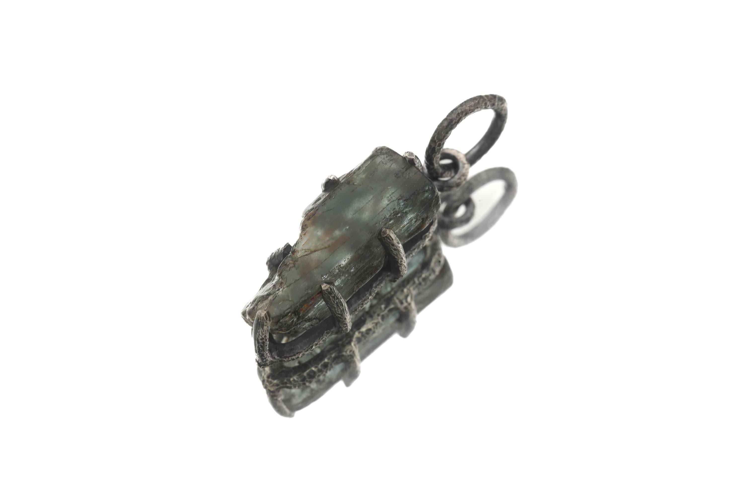 High Grade Blue Tourmaline pendant on white background showing raw Indicolite crystal and oxidized silver claw frame.