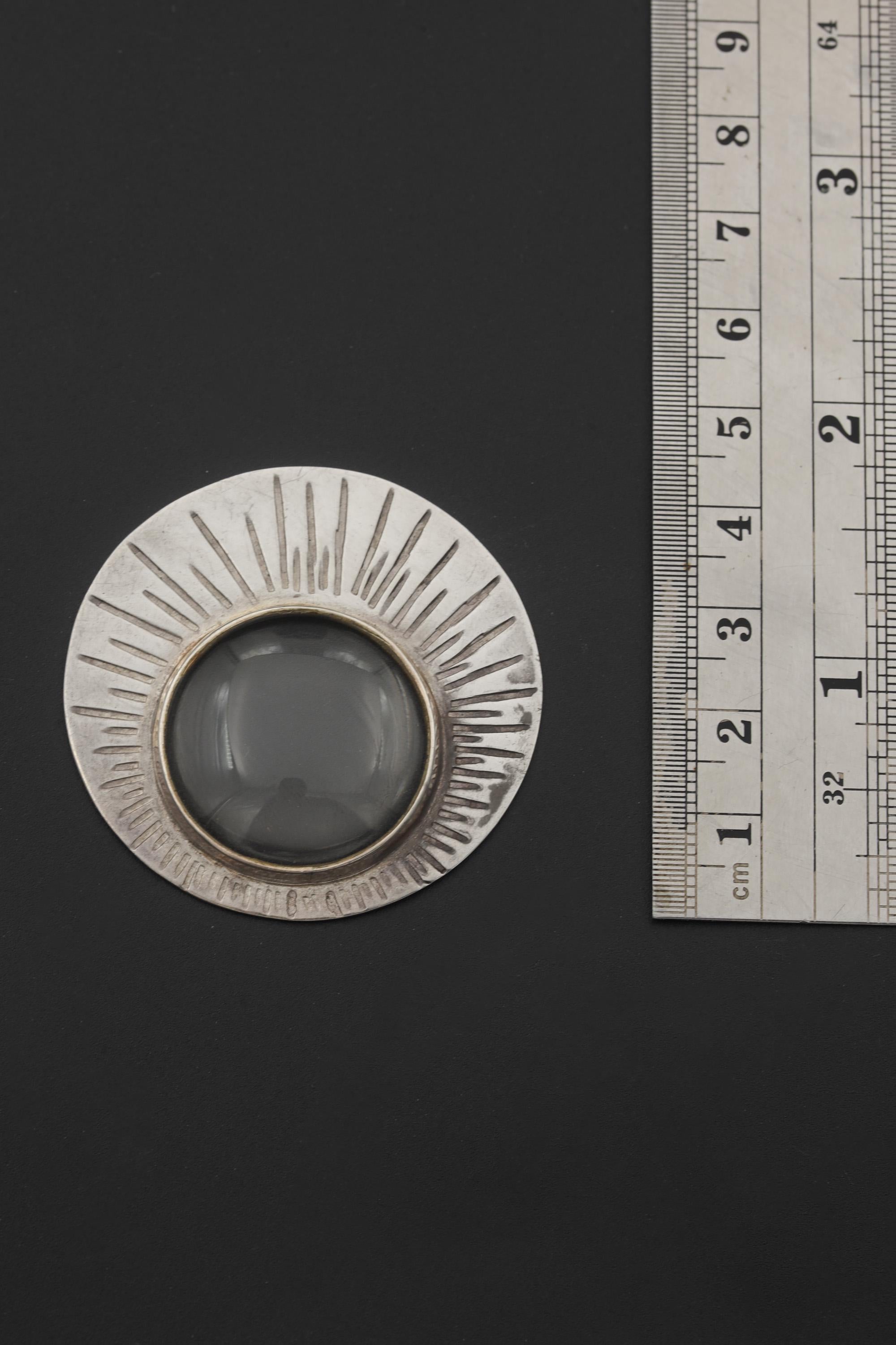 Detailed view of 5x optical magnifying glass pendant with oxidized sterling silver Sun ray texture.
