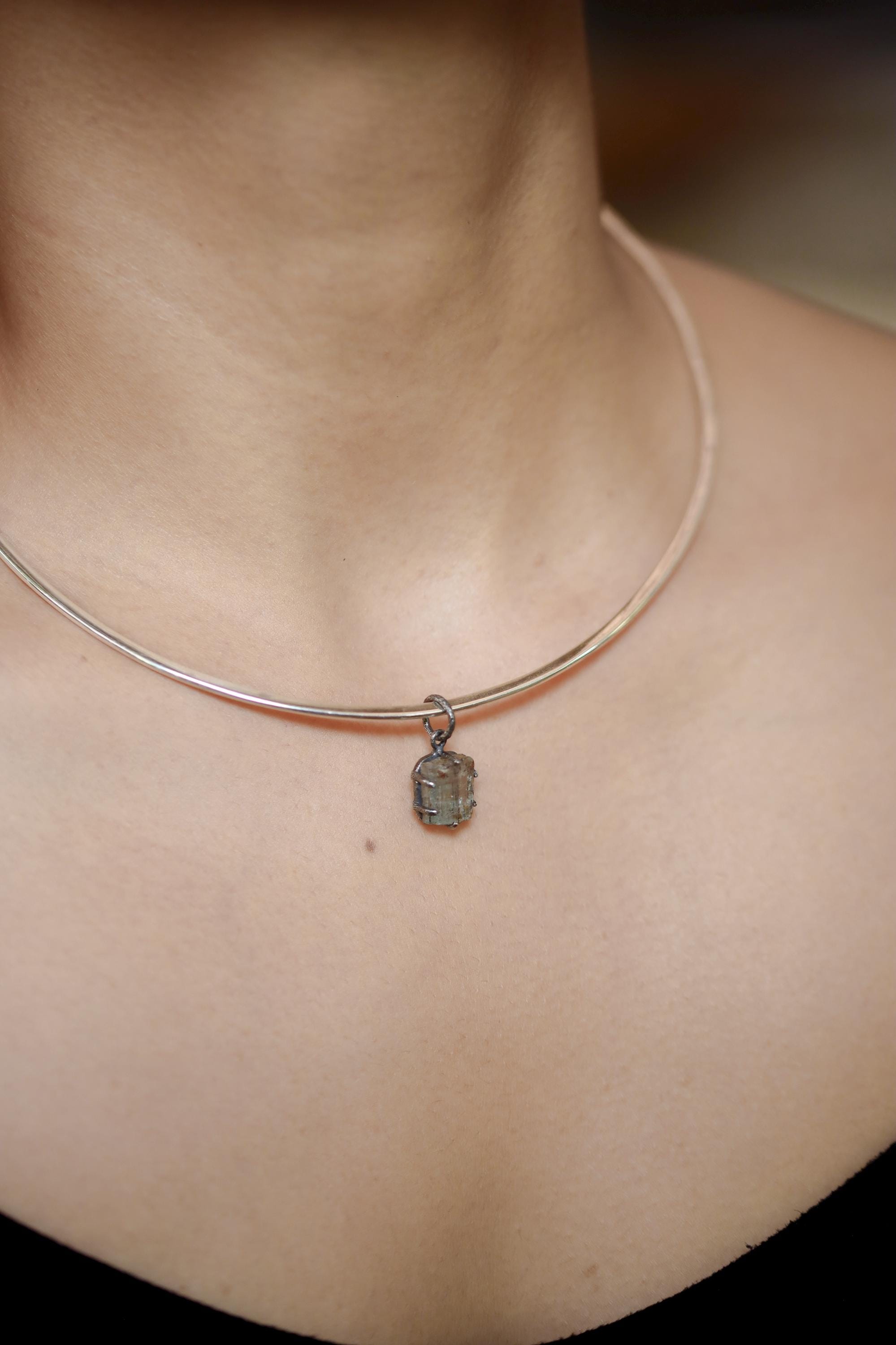 Australian Raw Gem Aquamarine pendant shown worn on a model, with compact oxidized silver setting and blue-green stone.