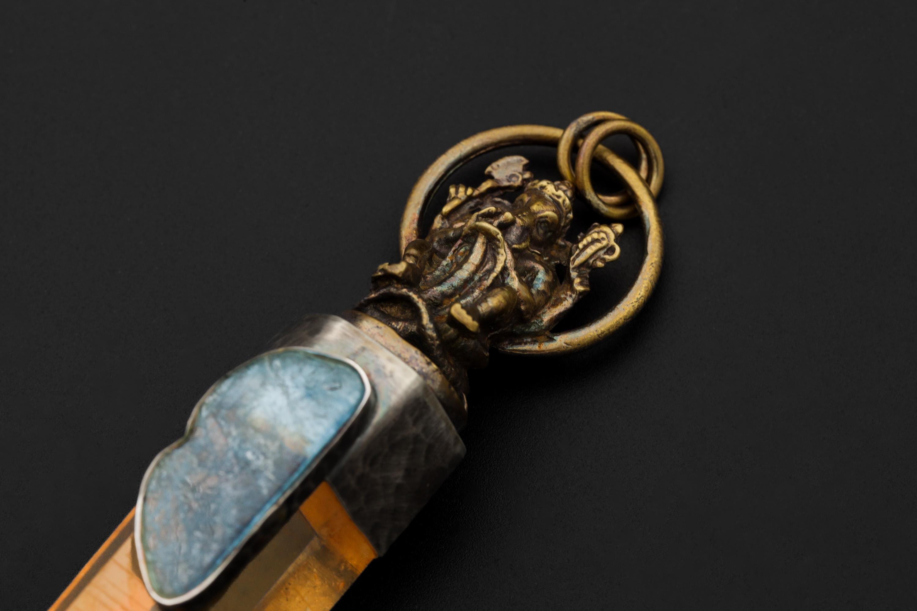 Close view of Ganesha pendant showing brass deity detail, oxidized silver cap, and Aquamarine cabochon.